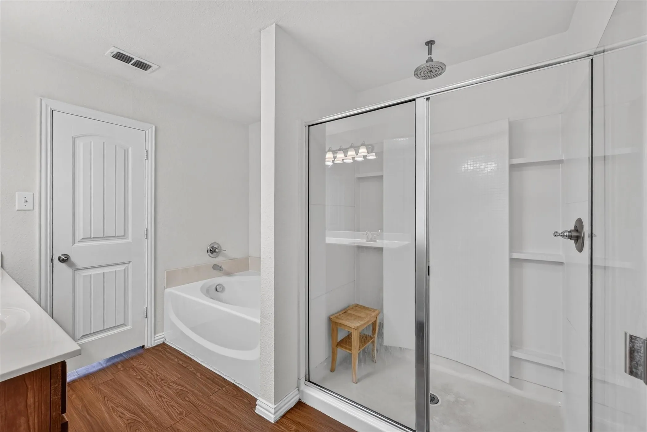 Full bathroom featuring walk-in glass-door shower, separate tub, and clean white tile finish