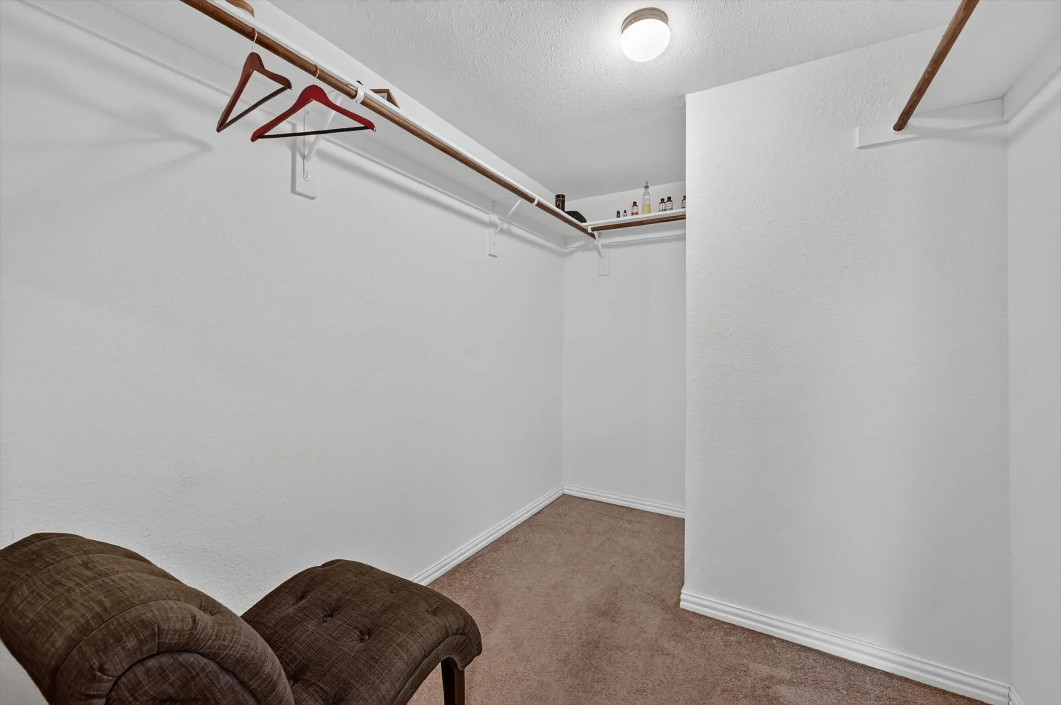 Walk-in closet storage space with custom shelving bars and neutral interior walls