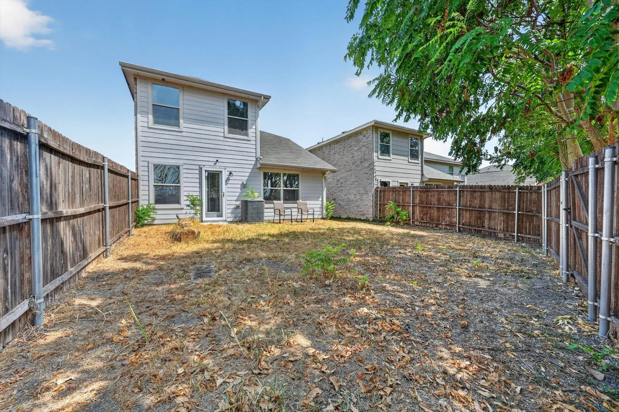 Rear exterior elevation of two-story brick house showing windows, roofline, and back yard lot