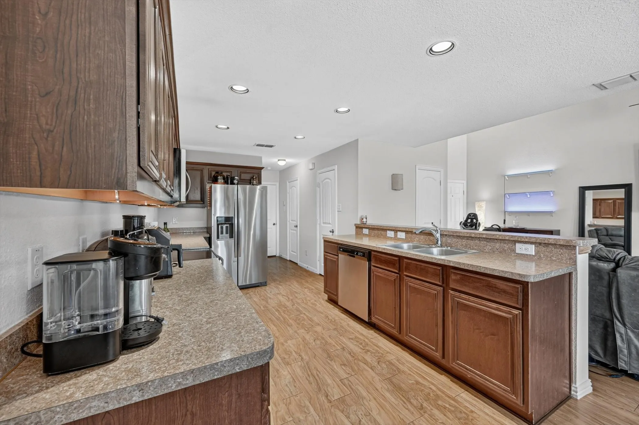 Kitchen featuring rich dark wood cabinets, stainless steel appliances, granite look countertops, and tile flooring