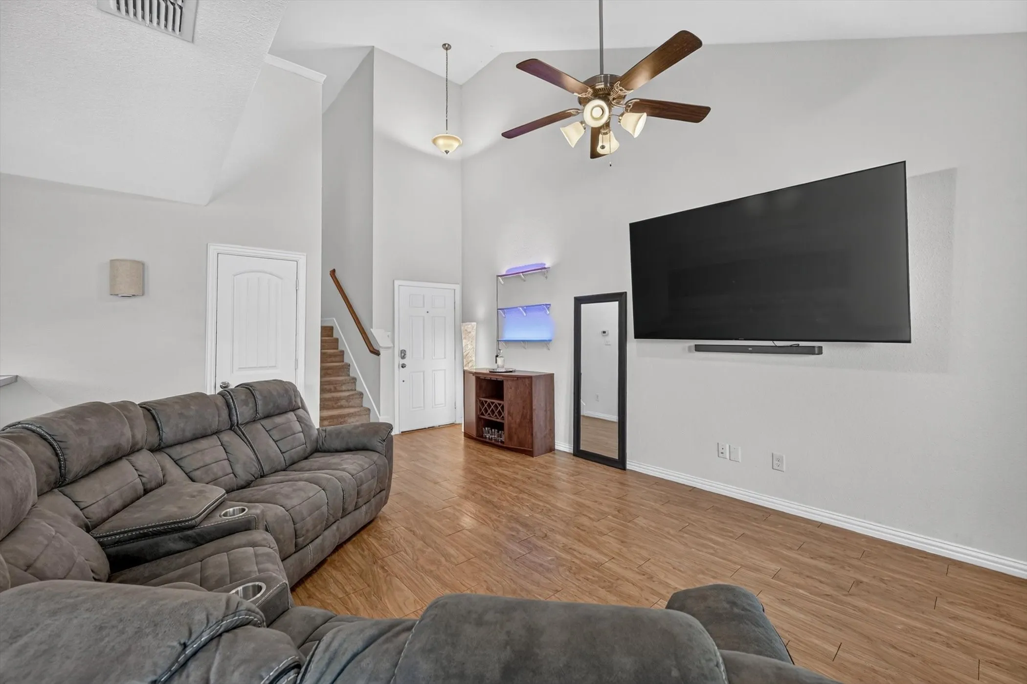 Living room interior showing comfortable sectional seating, wood flooring, and open floor plan access