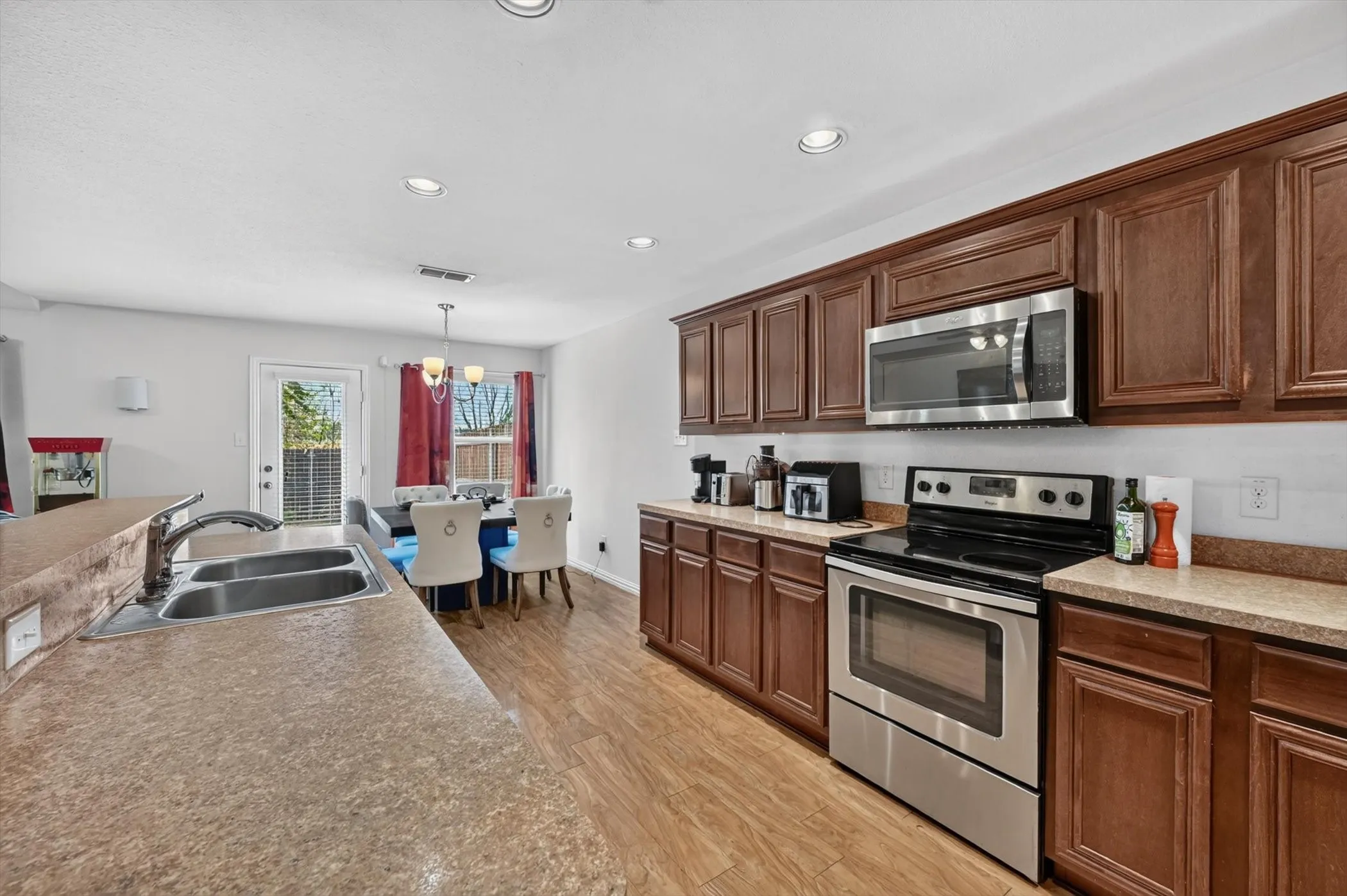 View from the kitchen looking into the open living areas, featuring a breakfast bar overhang, recessed lighting, and modern cabinetry.