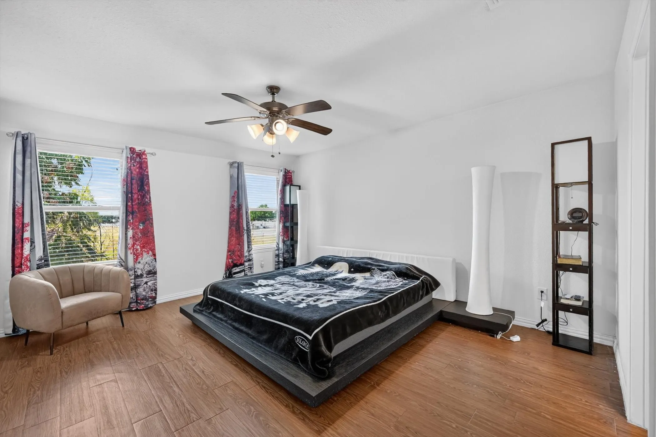 spacious bedroom with dark wood laminate flooring, large windows, ceiling fan, and modern neutral wall colors.