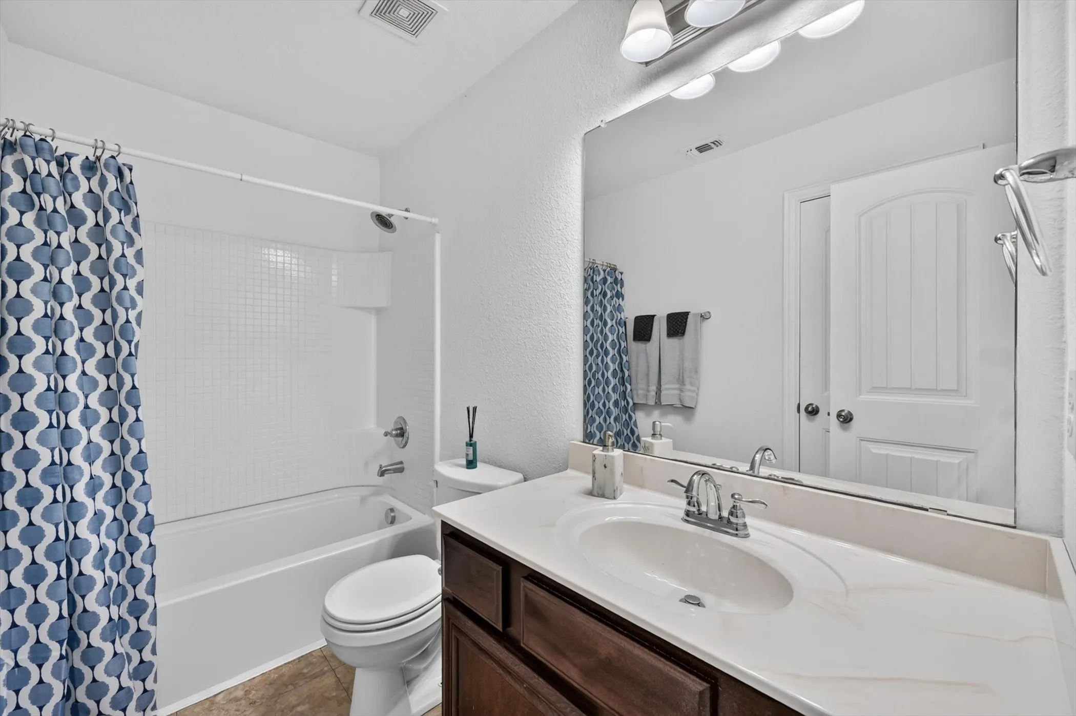 Close-up view of the bathroom vanity counter space, lower dark wood cabinetry, sink basin, and modern faucet hardware