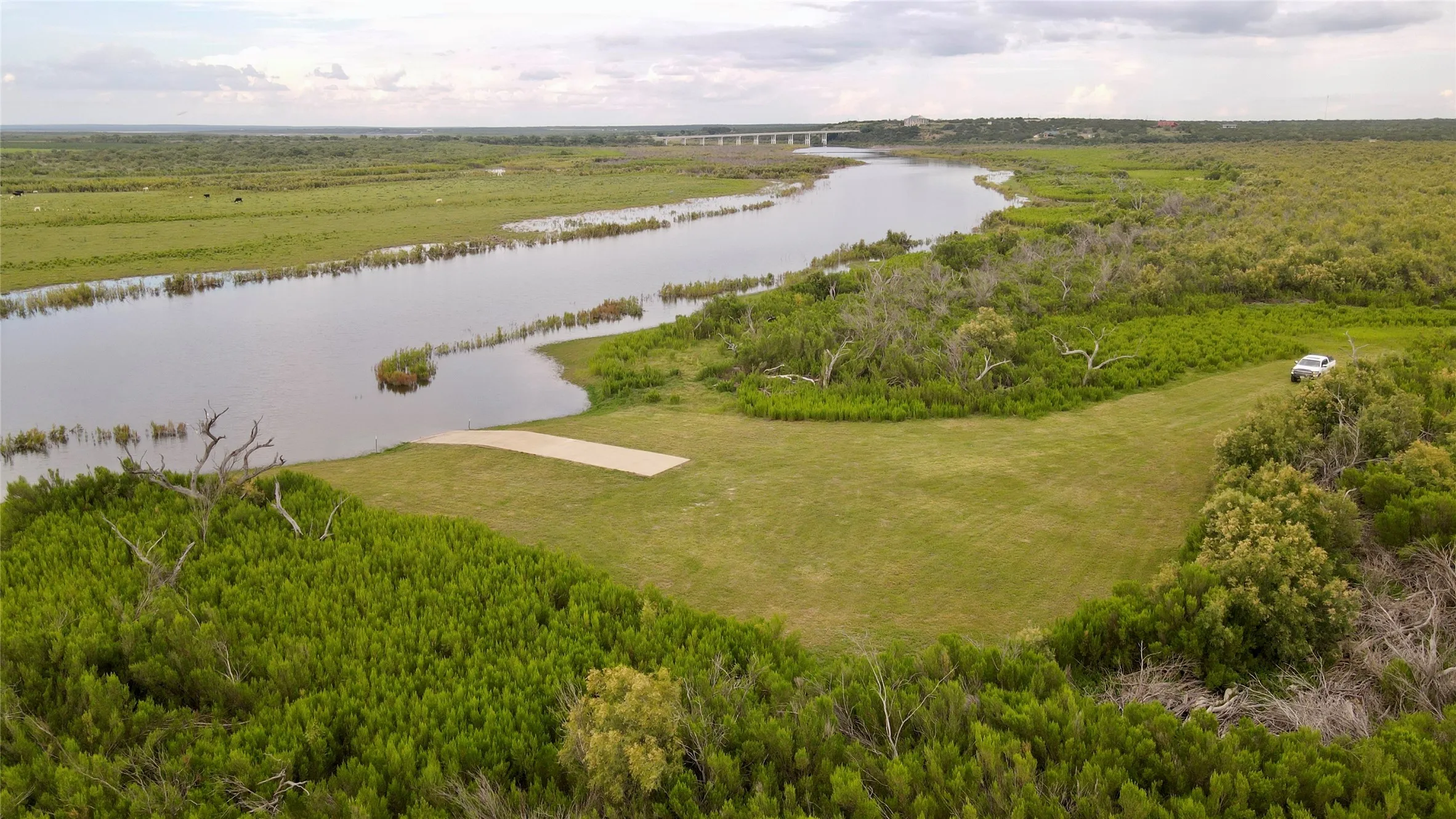 Drone / aerial view of a nearby body of water and a heavily wooded area
