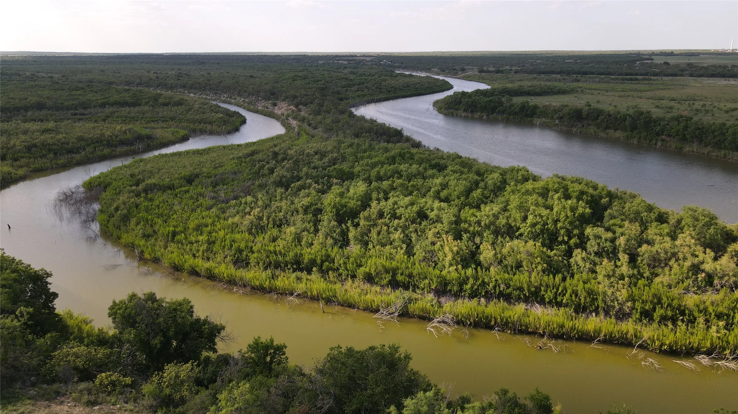 Drone / aerial view of a large body of water and a heavily wooded area