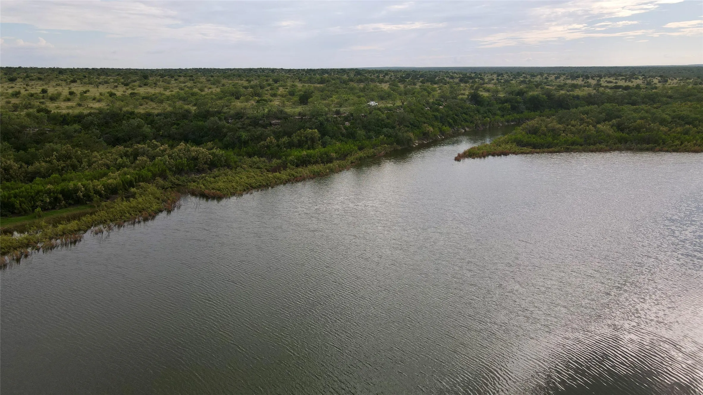 Drone / aerial view of a heavily wooded area and a large body of water