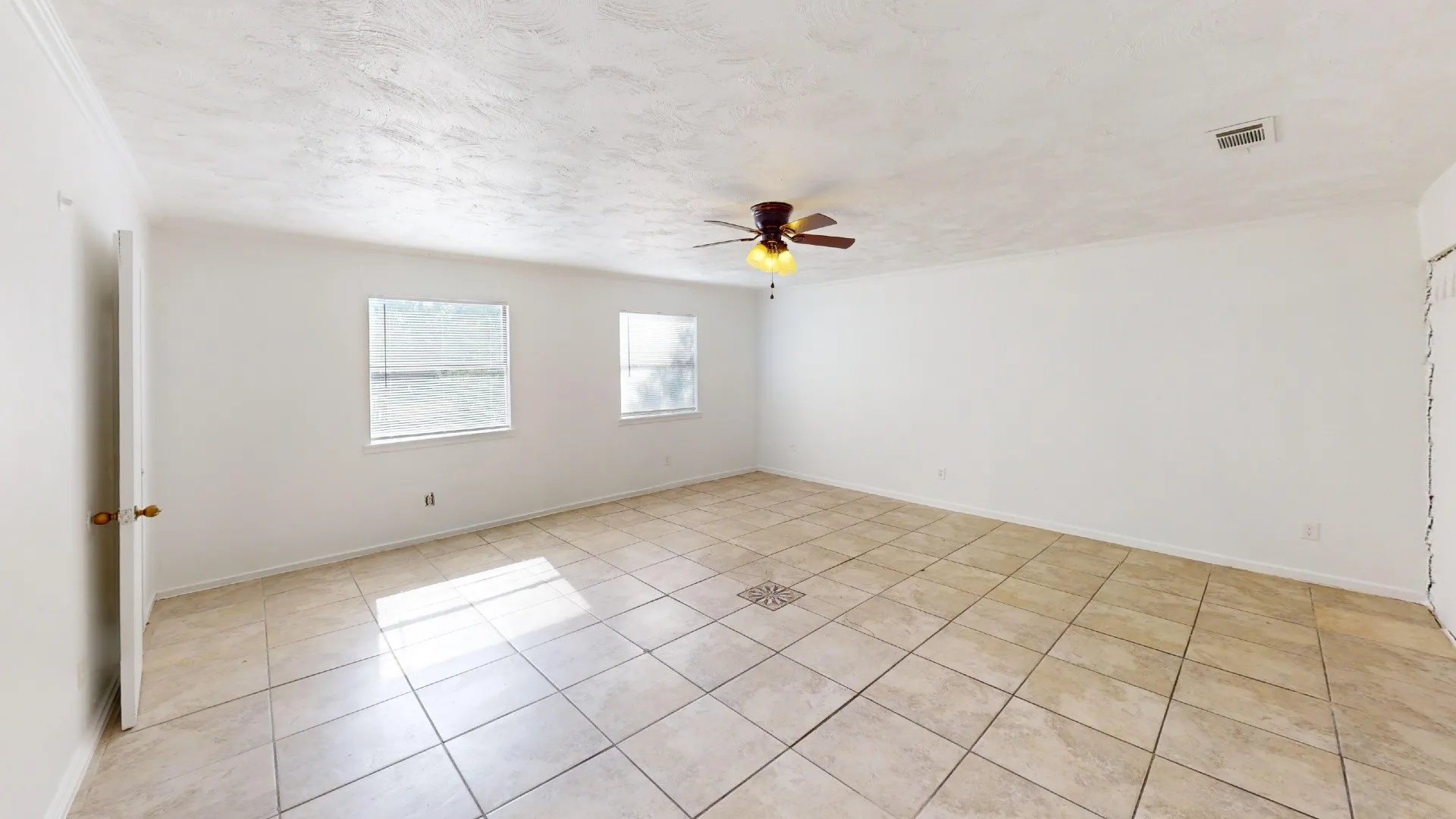 Spacious room featuring tile flooring, a ceiling fan with integrated lighting, and multiple windows