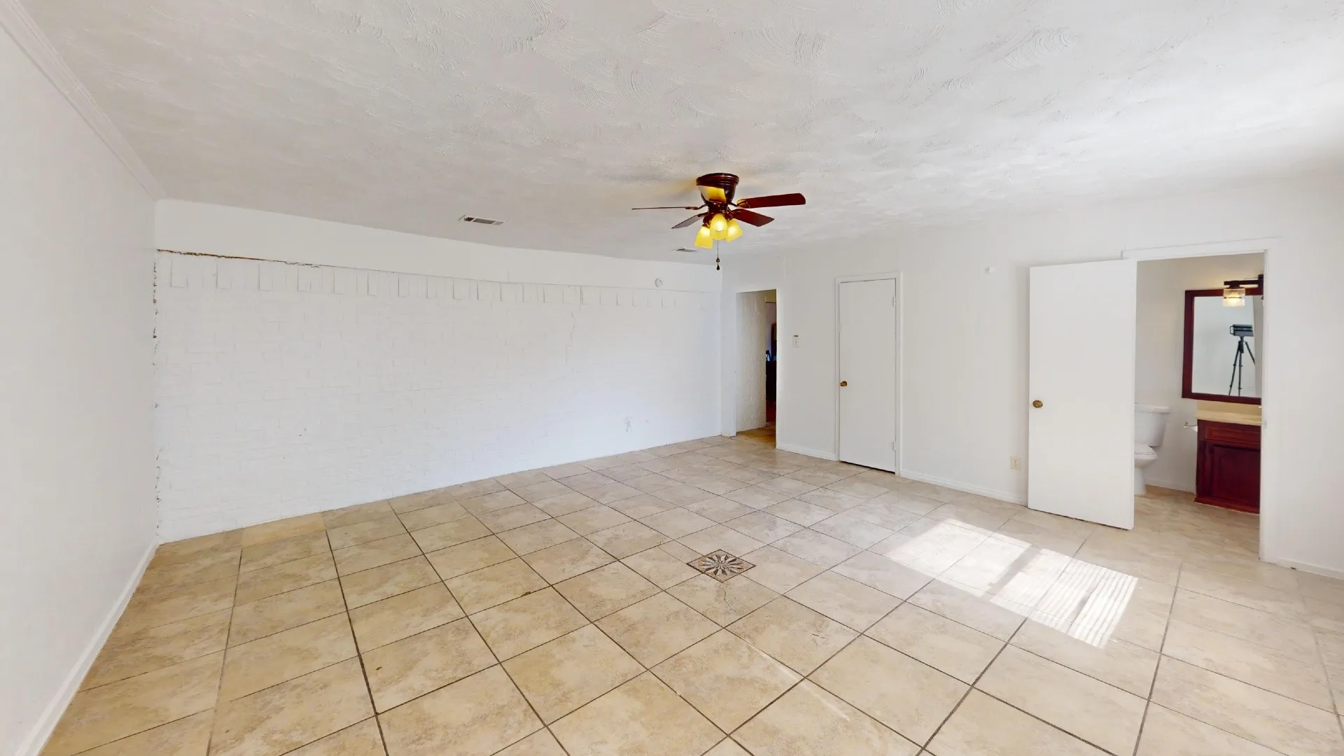 Spacious room featuring tile flooring, a ceiling fan with integrated lighting, and white painted walls