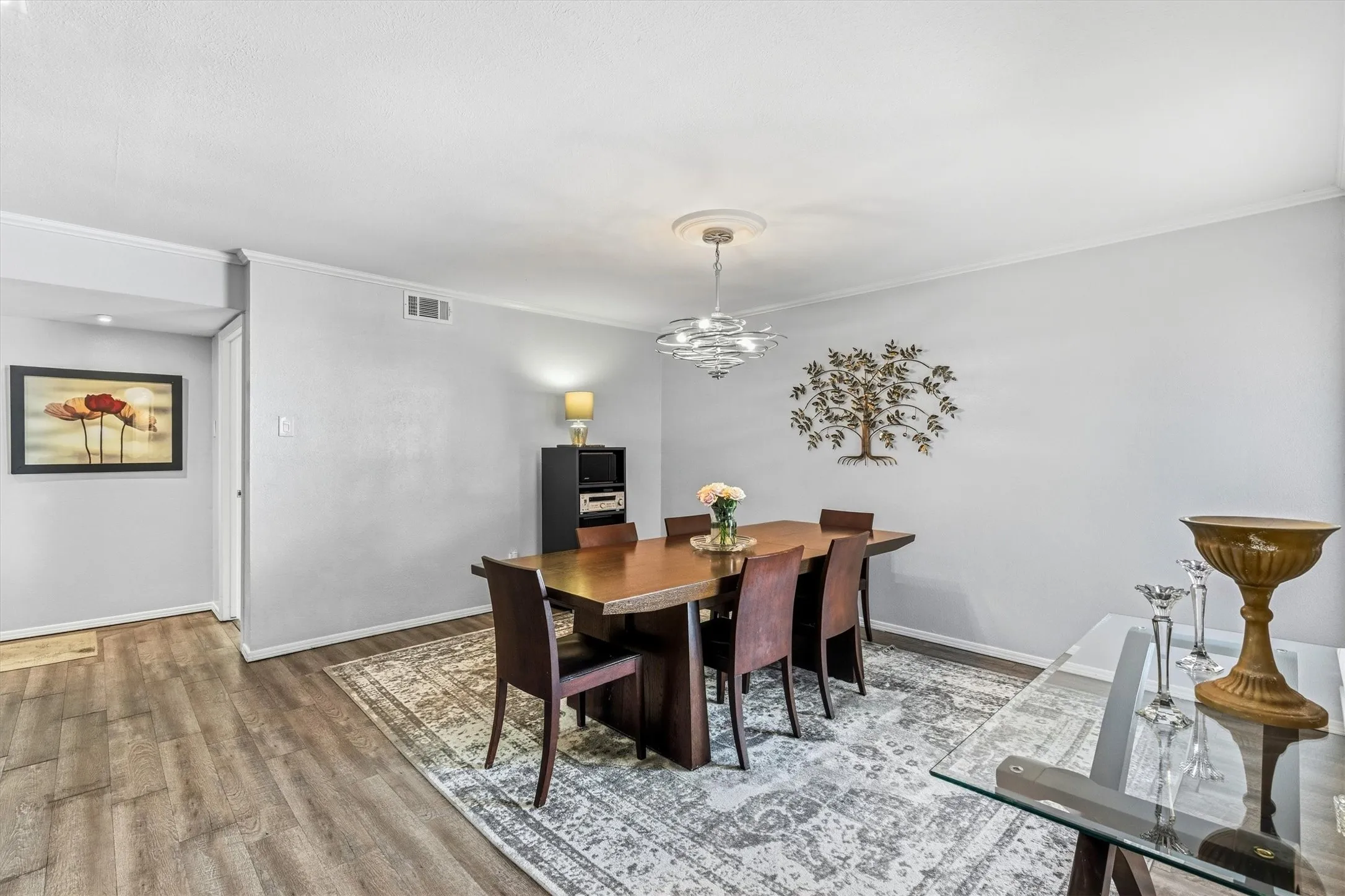 Wood-finish flooring, crown molding, and a decorative ceiling medallion complement the light-toned walls
