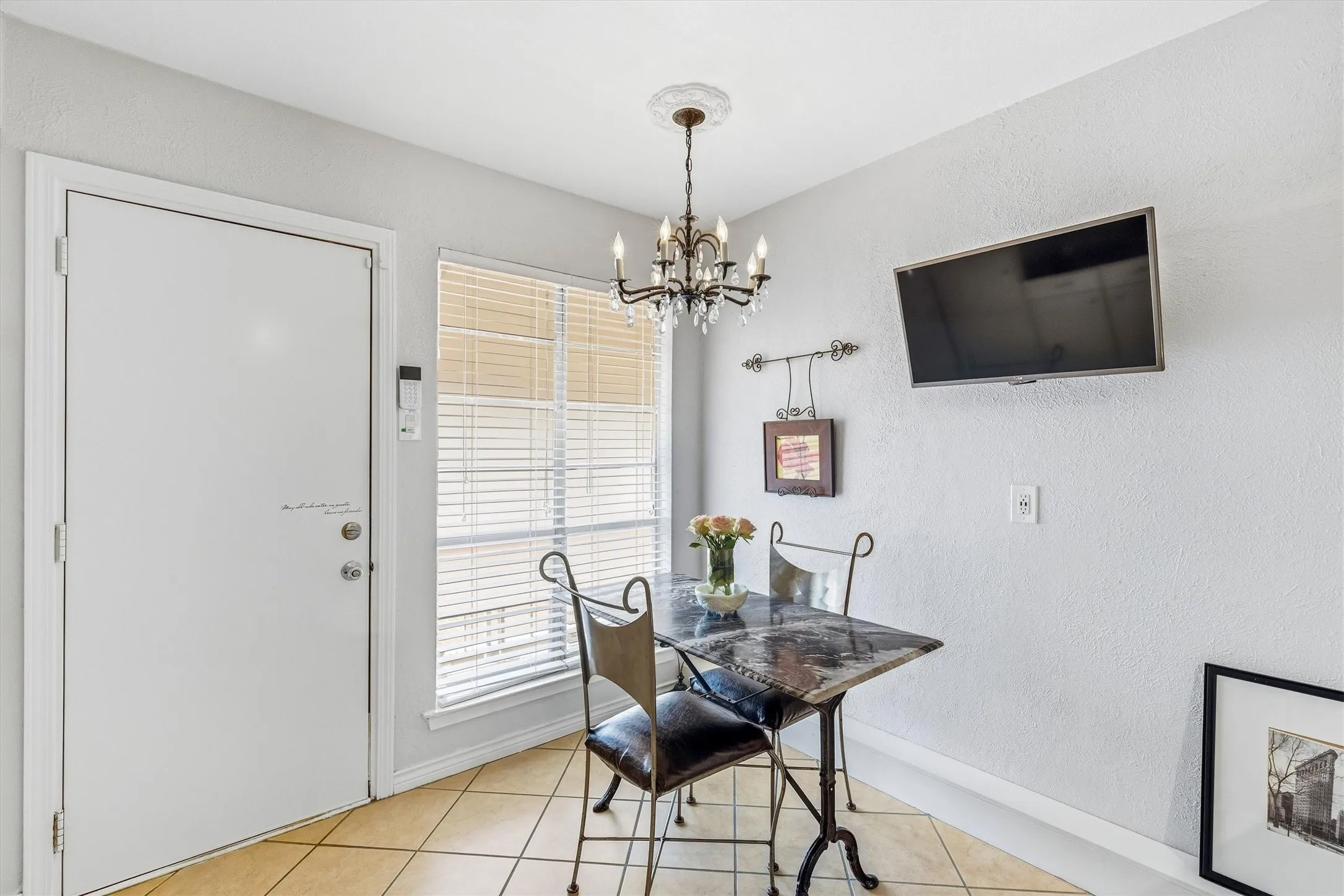 Tile flooring with a chandelier fixture, window with blinds, and white door