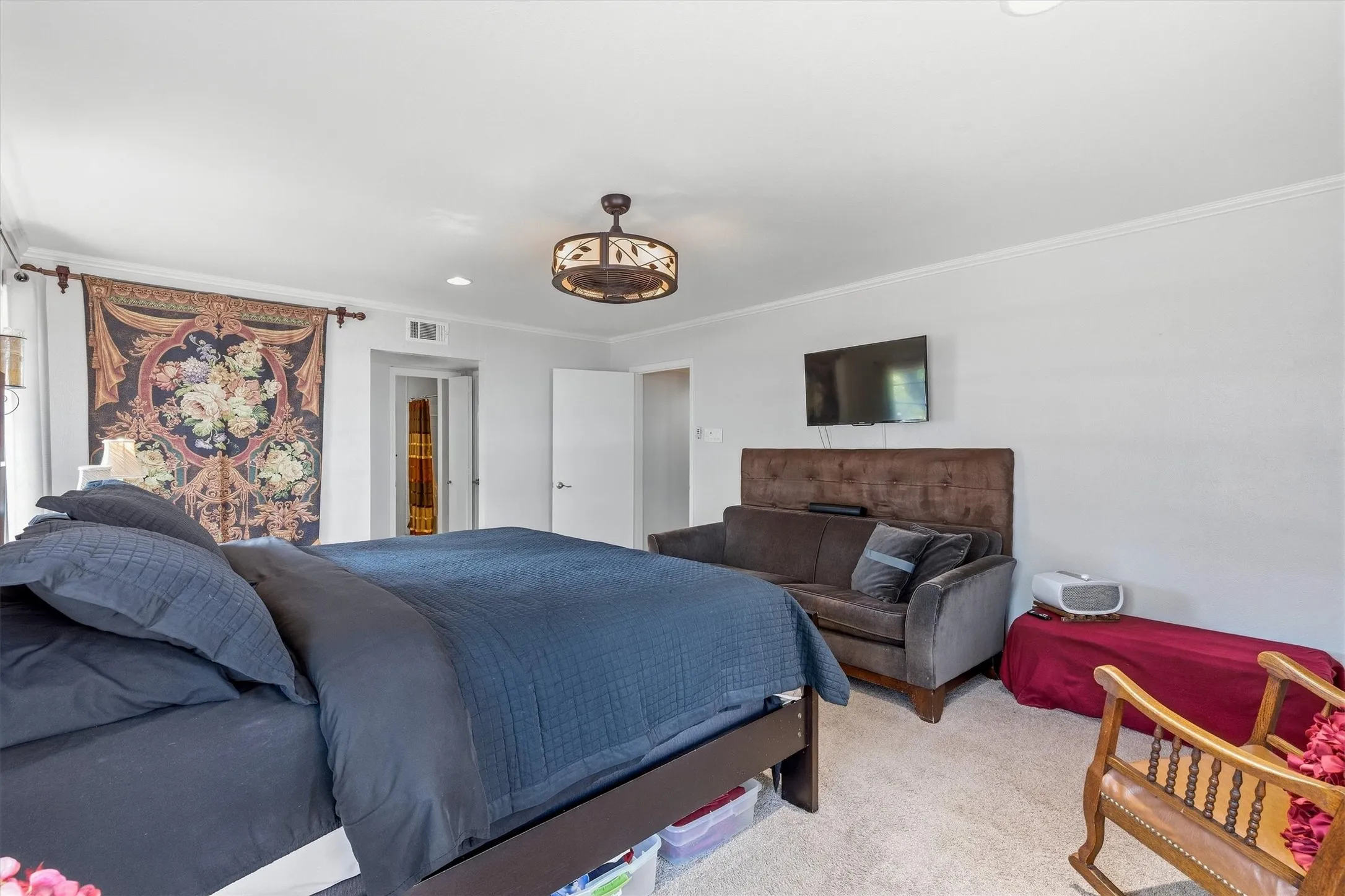 White walls featuring crown molding, carpeted flooring, and a decorative ceiling light fixture