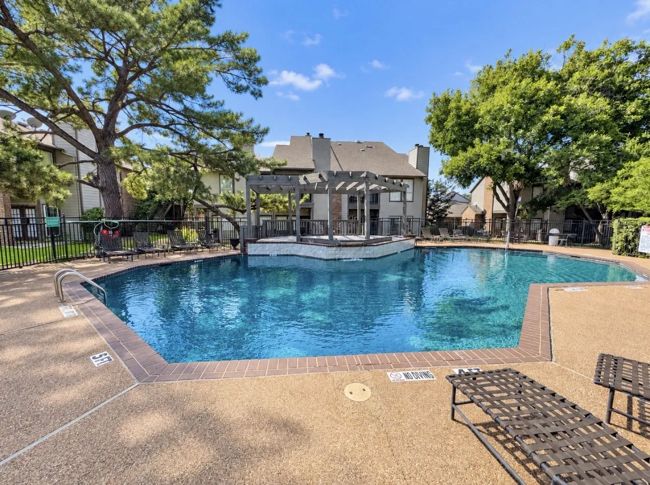 Large outdoor swimming pool with a surrounding textured concrete deck and a stone-clad raised hot tub