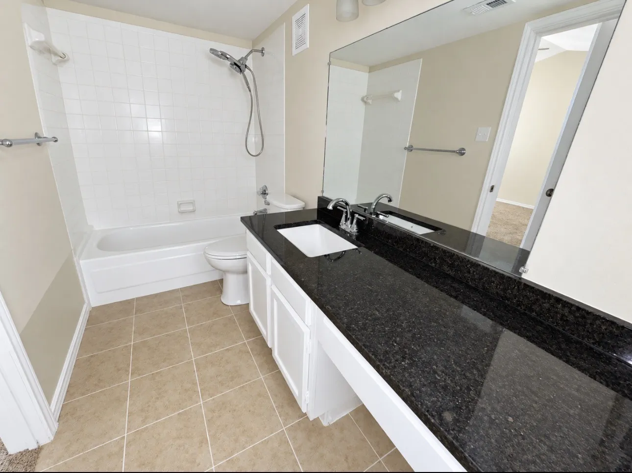 Spacious bathroom with a large vanity featuring a dark stone countertop and an integrated sink