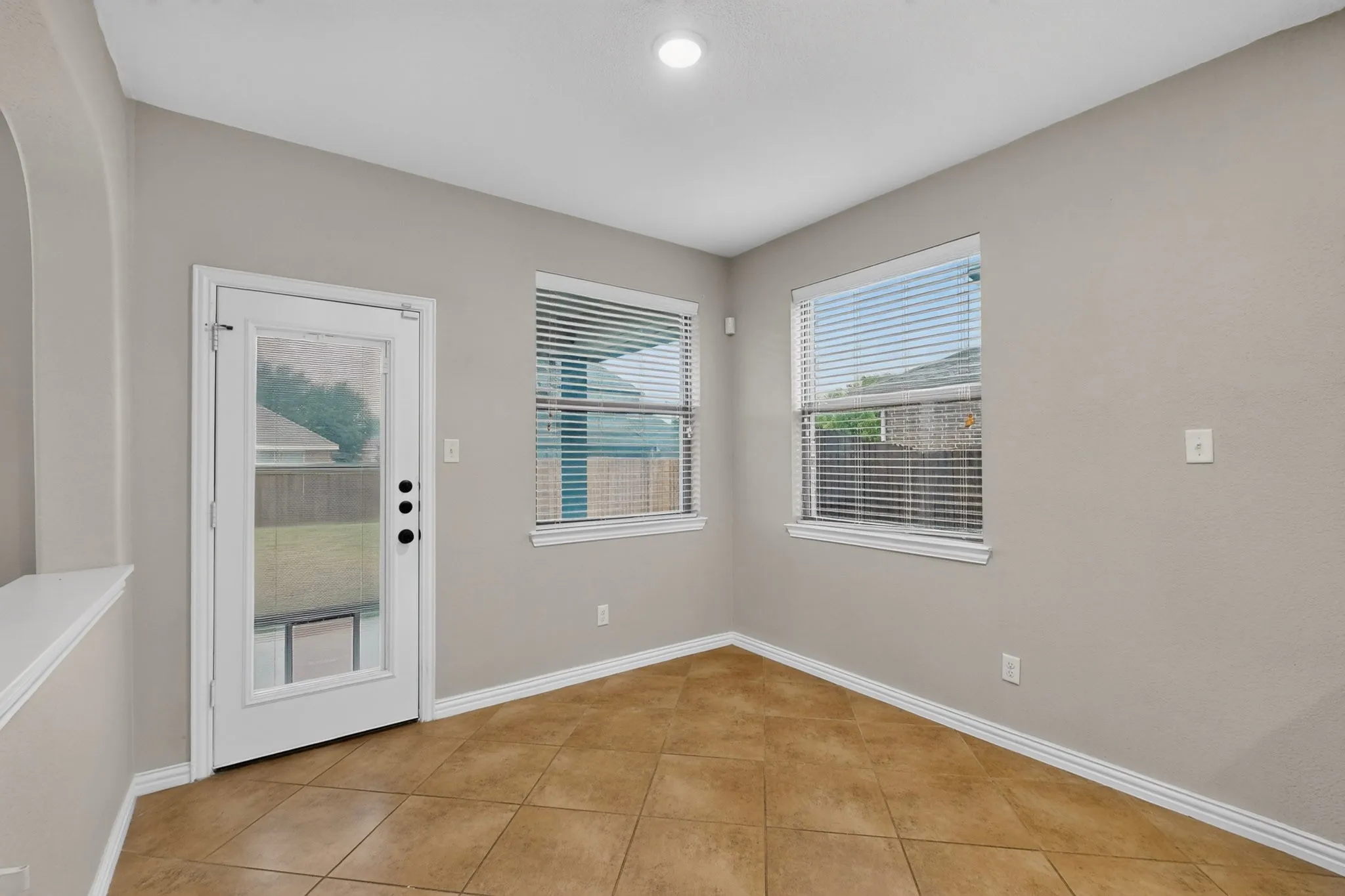 Recessed lighting, light gray wall paint, white trim, two windows with blinds, and tile flooring