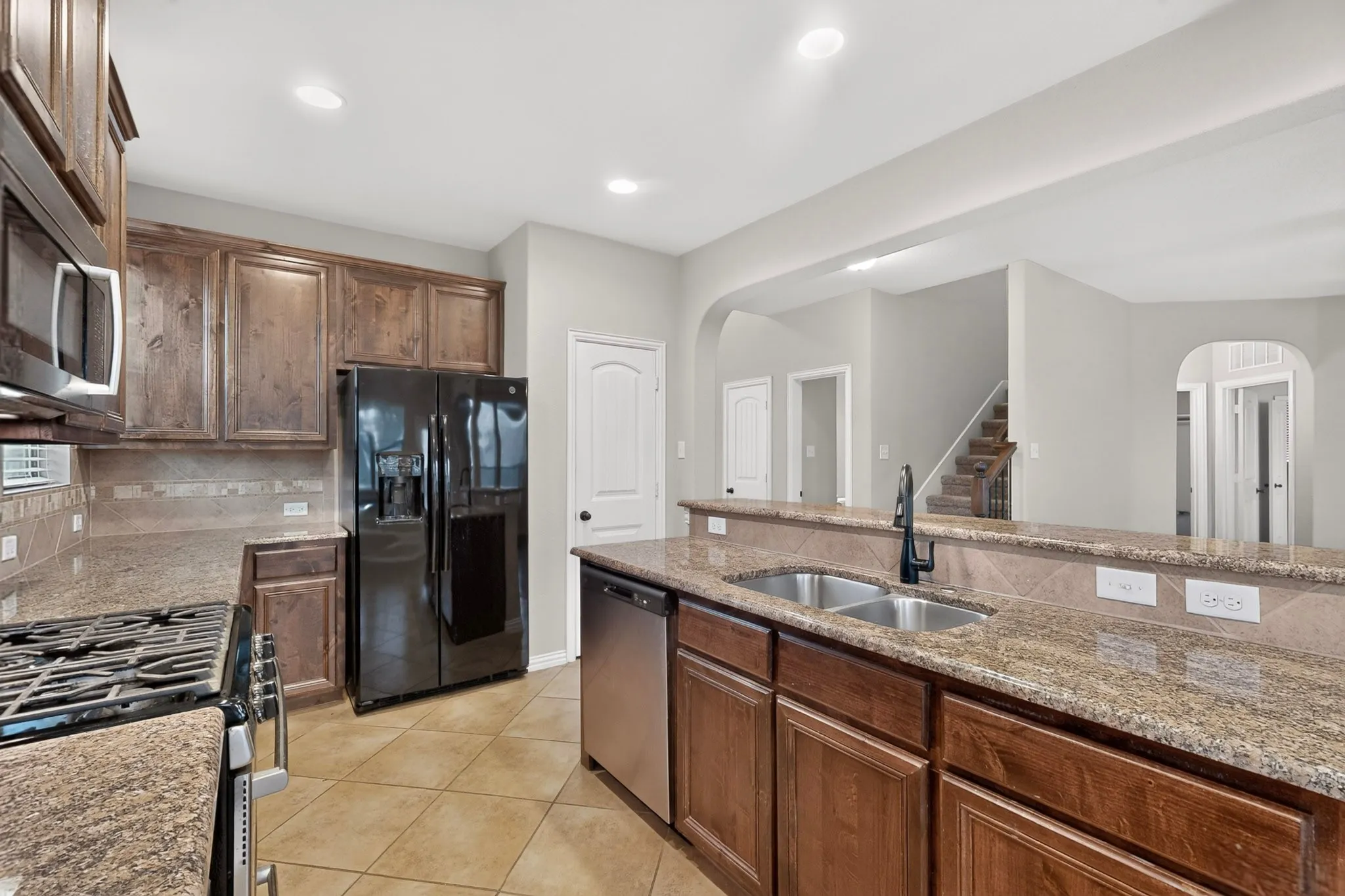 Kitchen featuring wood cabinetry, granite countertops, tile flooring, and stainless steel appliances
