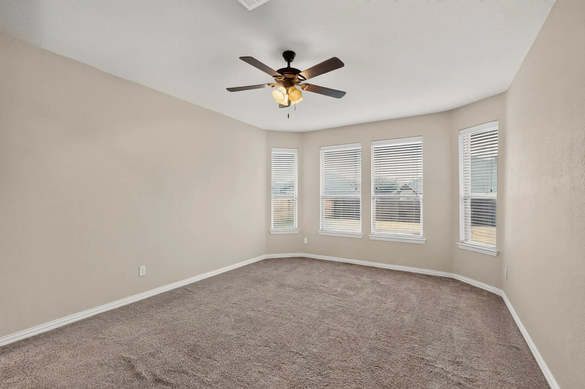 Bright corner room bathed in natural light through multiple casement windows with plantation shutters