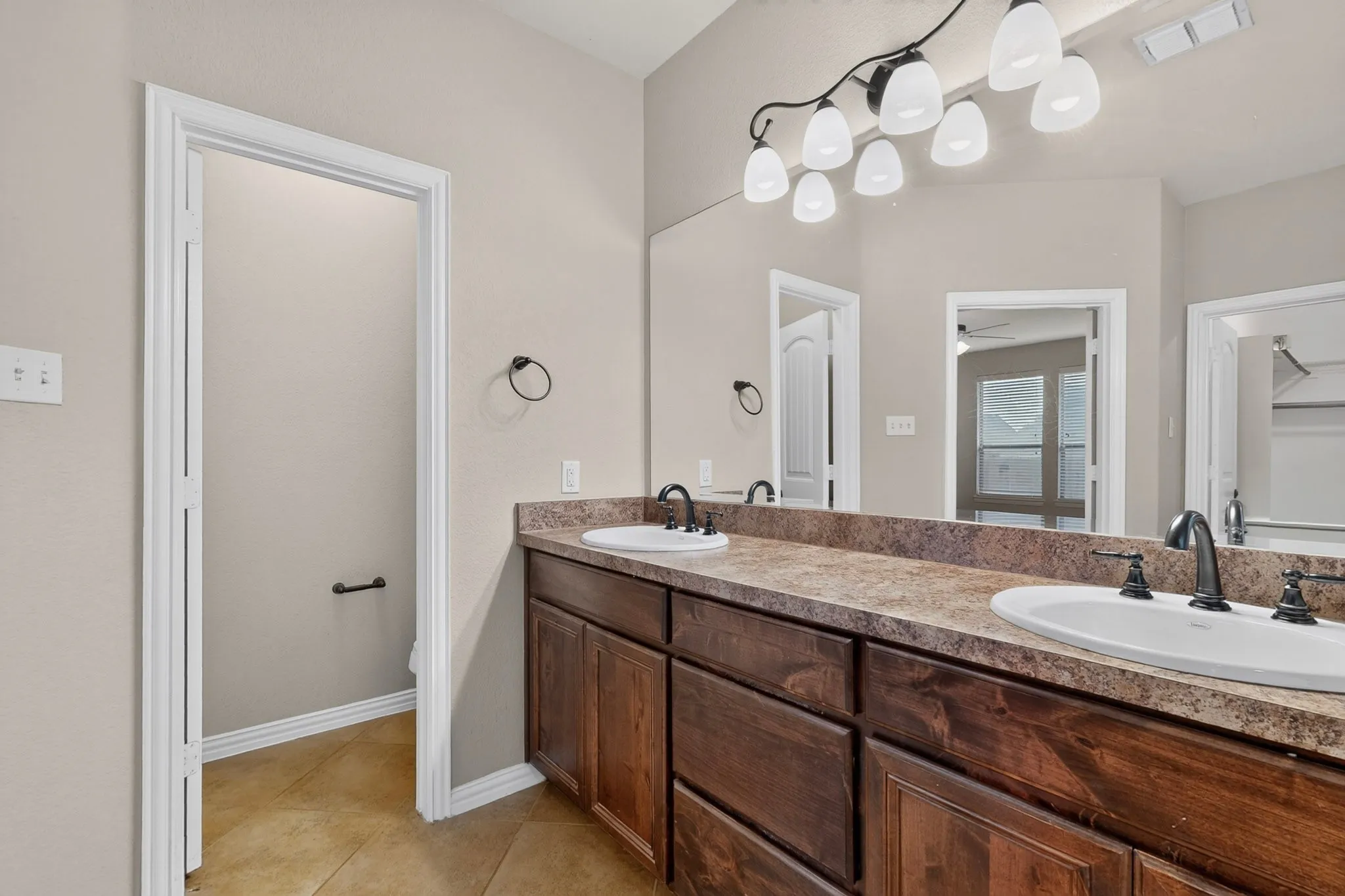Dual under-mount sinks with dark bronze fixtures, set into a stone-finish countertop