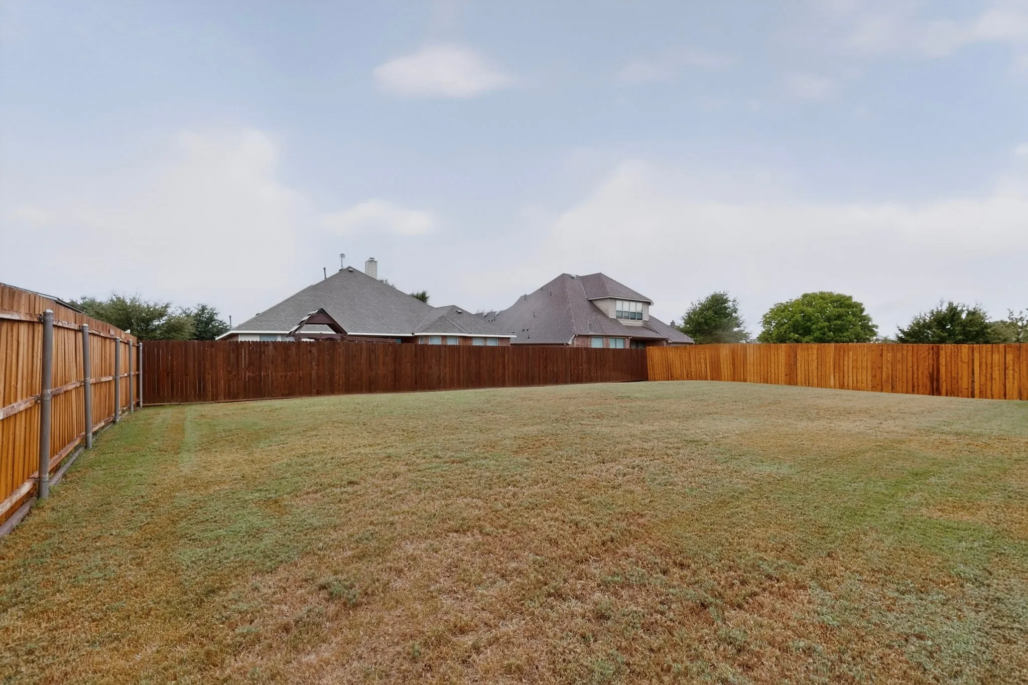 Expansive grassy yard with wood privacy fencing