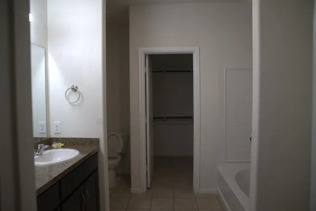 Vanity with integrated sink, dark wood-finish cabinetry, and stone-finish countertop