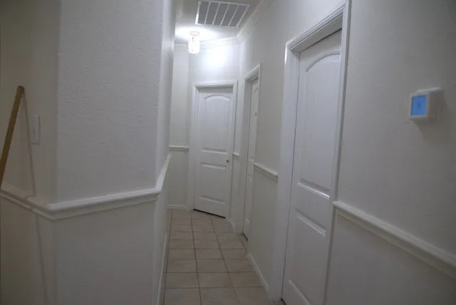 Hallway with wainscoting, crown molding, arched panel doors, recessed lighting, and tile flooring