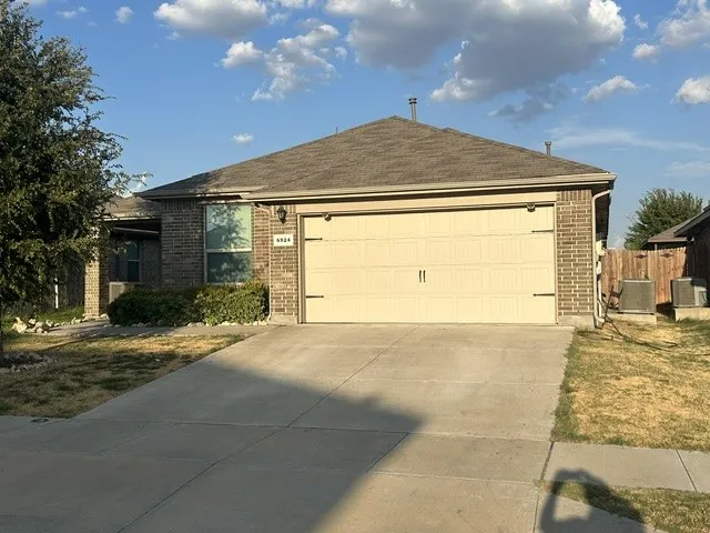 Brick exterior with a peaked shingle roof, attached garage, and concrete driveway