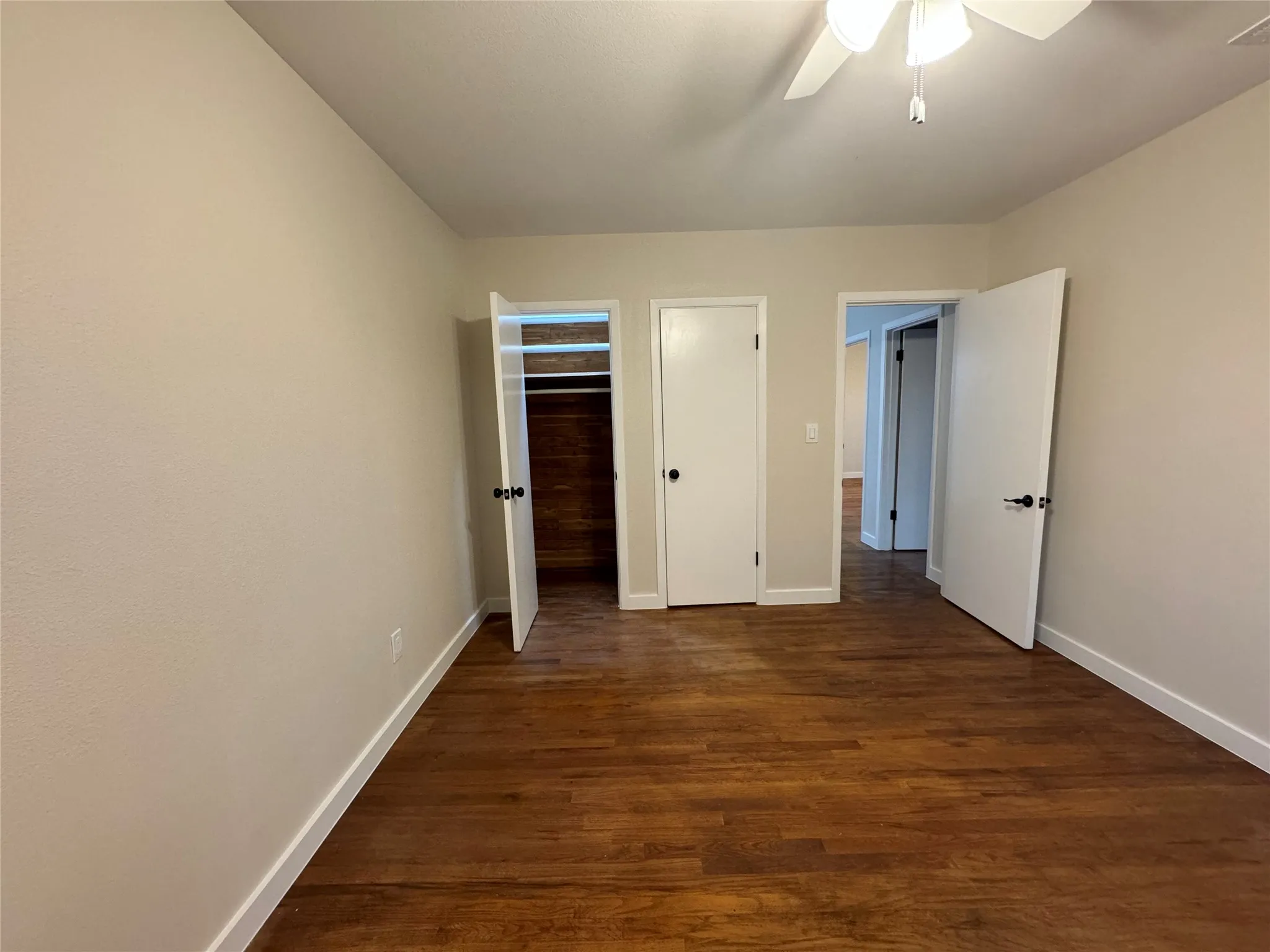 Unfurnished bedroom featuring ceiling fan, a closet, and dark hardwood / wood-style flooring