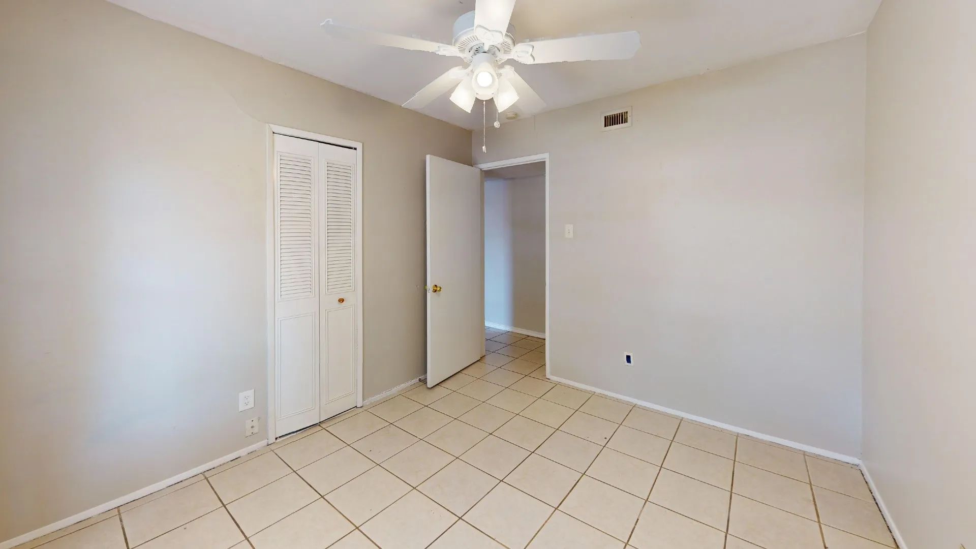 Neutral tone wall finish, ceramic tile flooring, ceiling fan with integrated lighting, louvered bi-fold closet doors, and a paneled interior door
