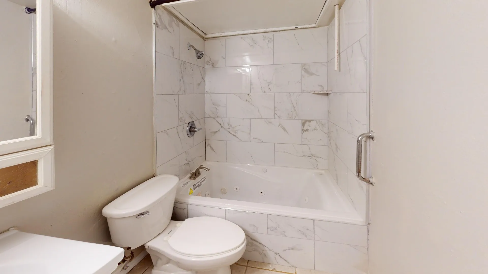 Bathtub with integrated jets, white subway tile surround, glass shower enclosure, built-in shower niche, and wall-mounted shower head
