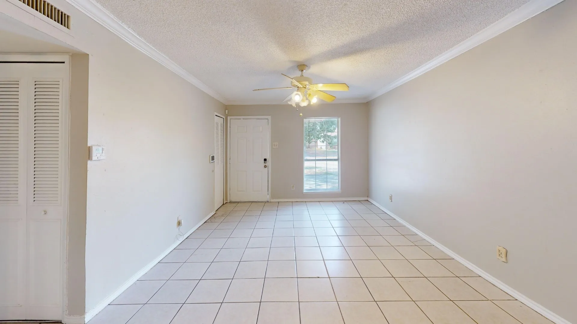 Ceramic tile flooring, crown molding, ceiling fan with light fixture, louvered bi-fold doors, and a window providing natural light