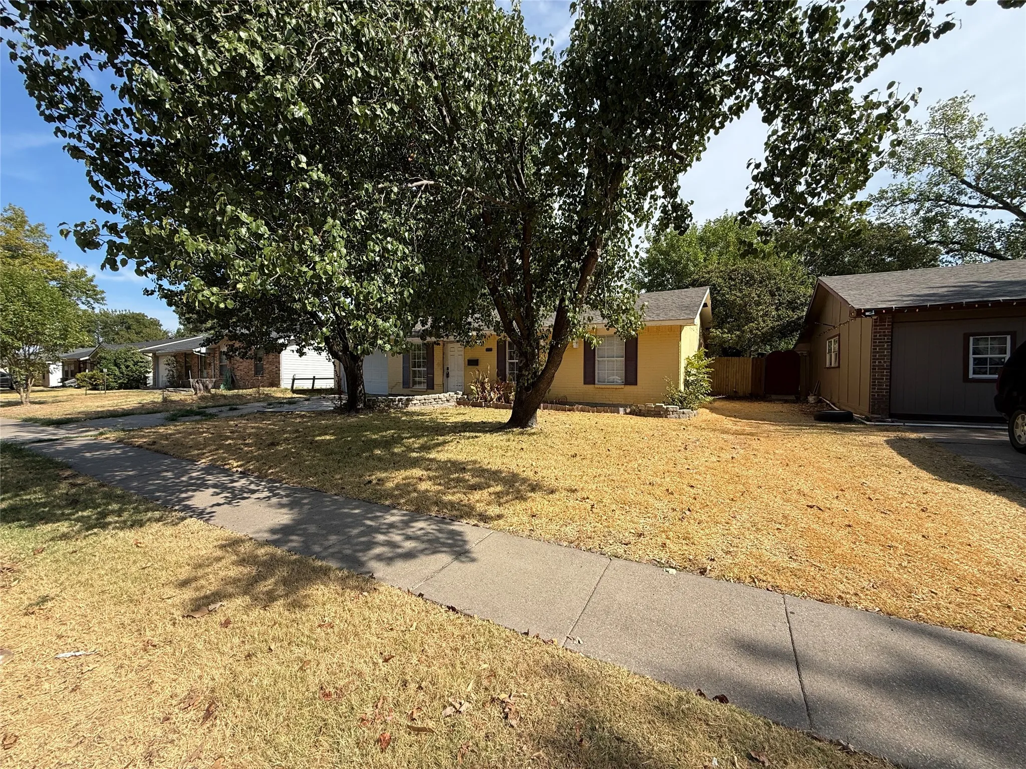 Single-story residence with a yellow facade, dark shutters, and a covered front entry
