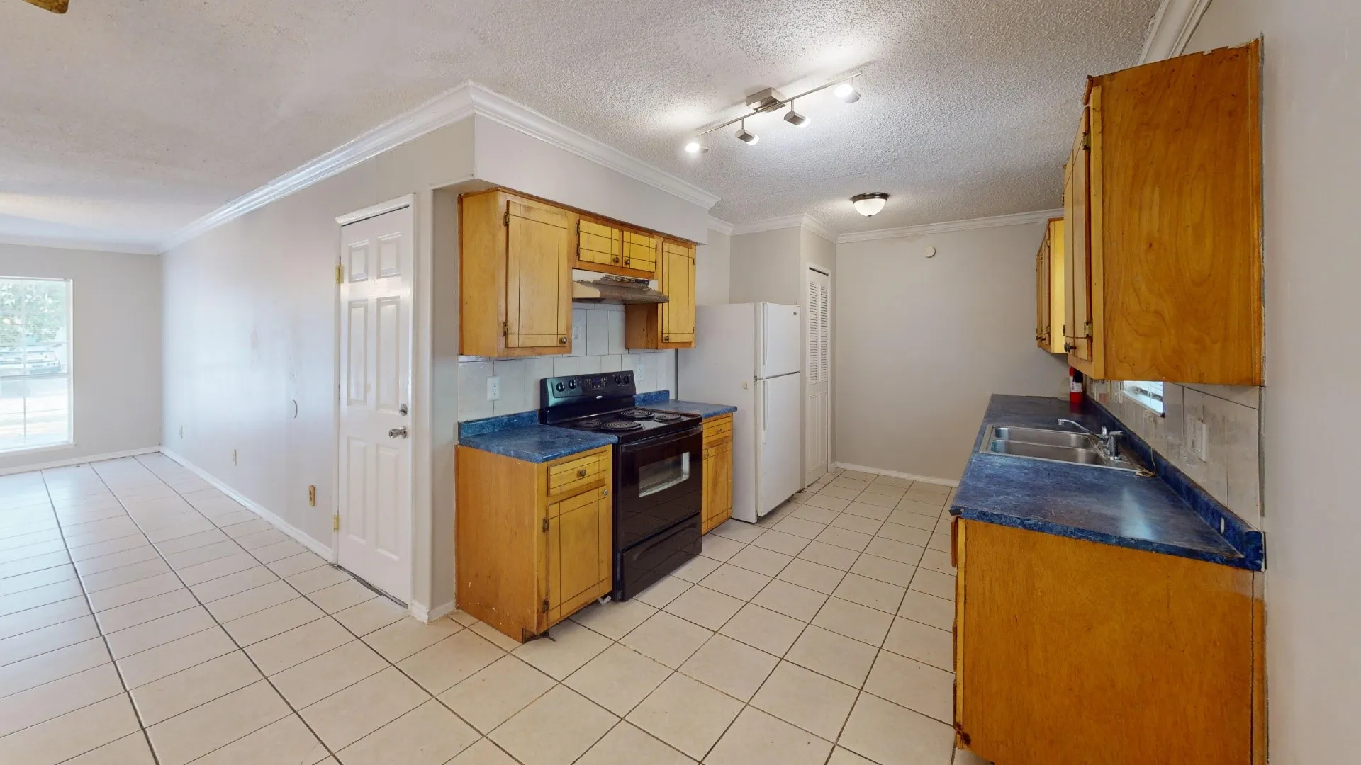 Kitchen with wood-finish cabinetry, blue countertops, and white tile flooring