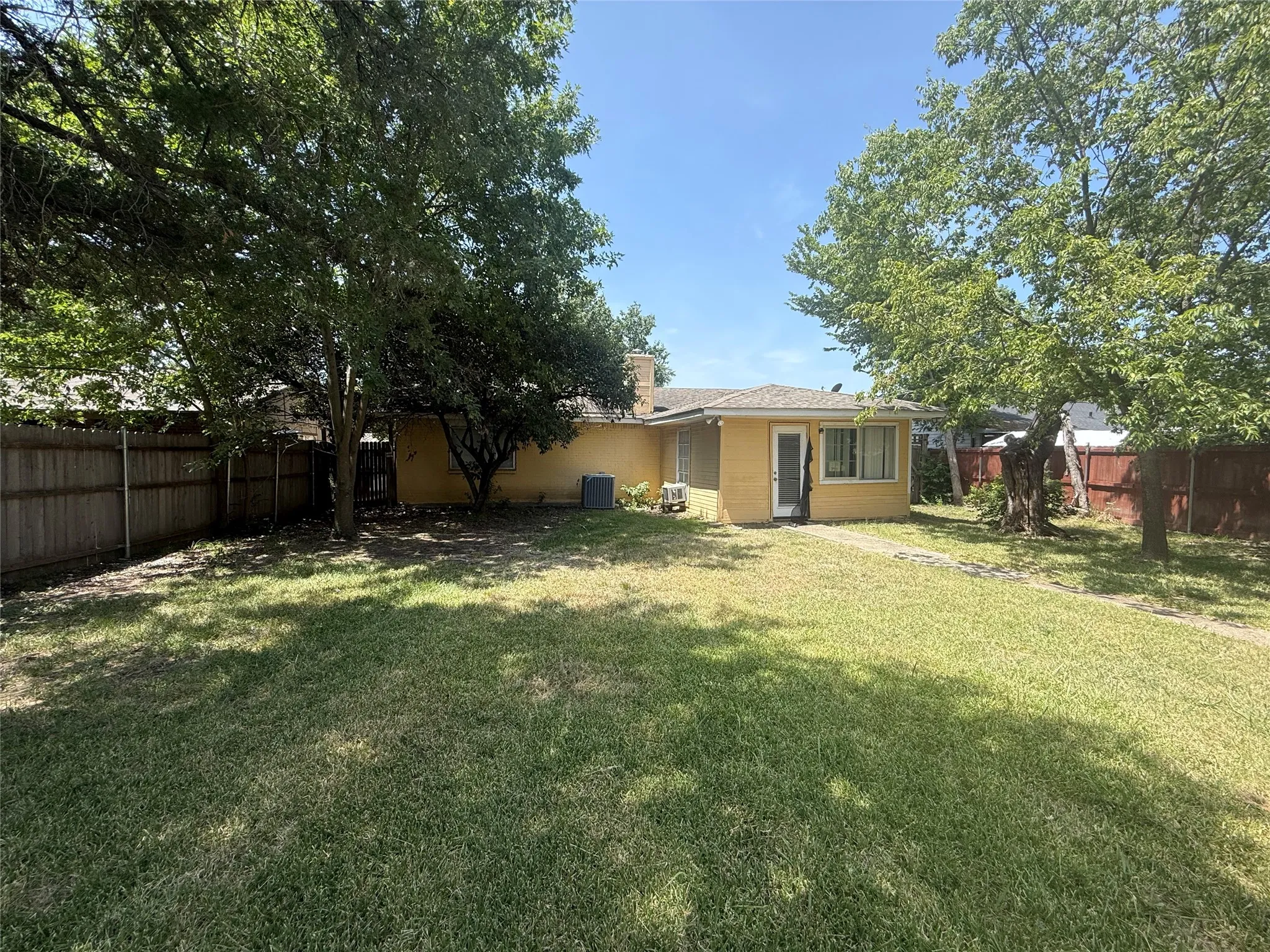 Expansive grassy yard framed by mature trees