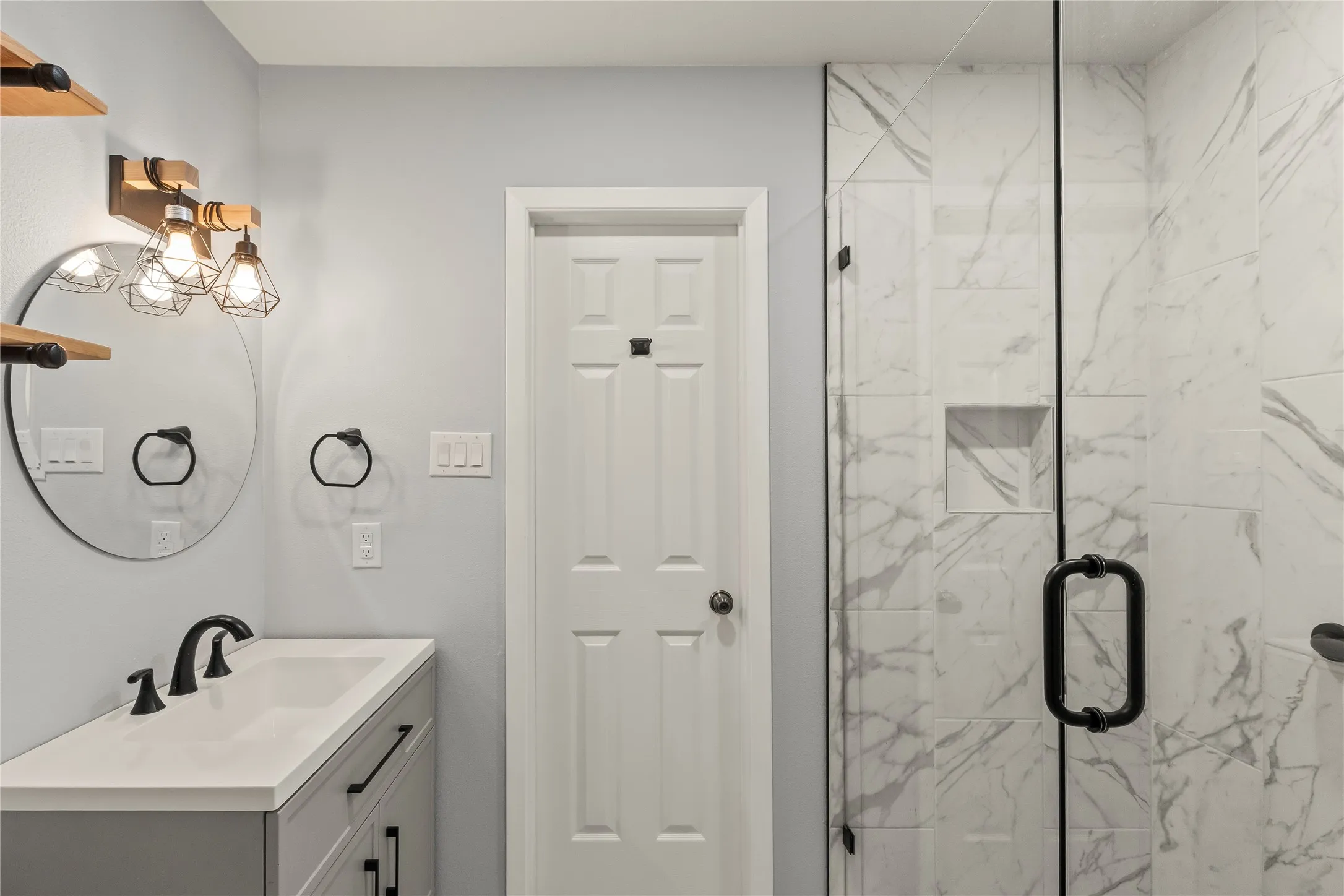 Custom vanity with integrated sink, black fixtures, and round mirror