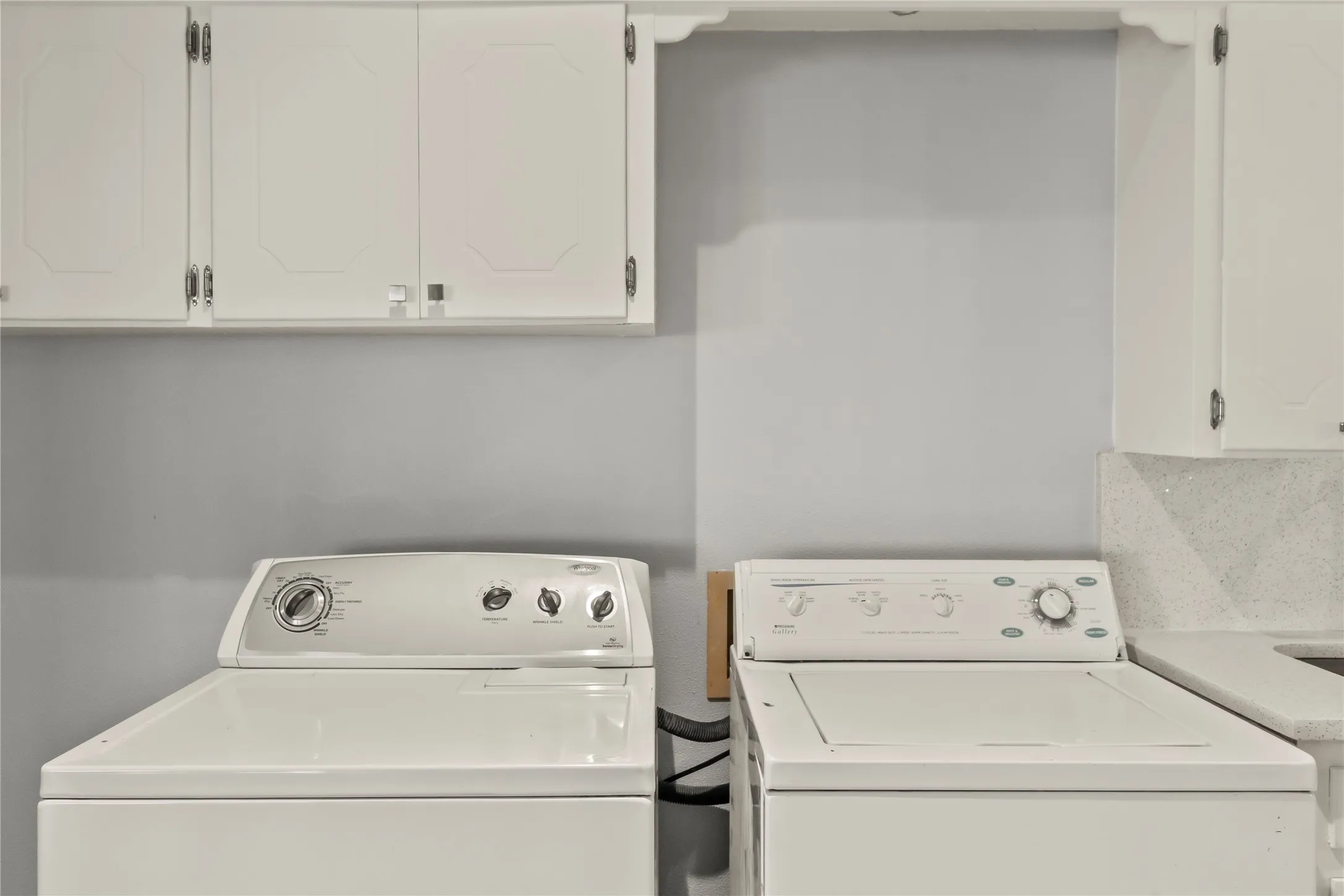 White upper cabinetry, light-toned wall, and light-colored countertop