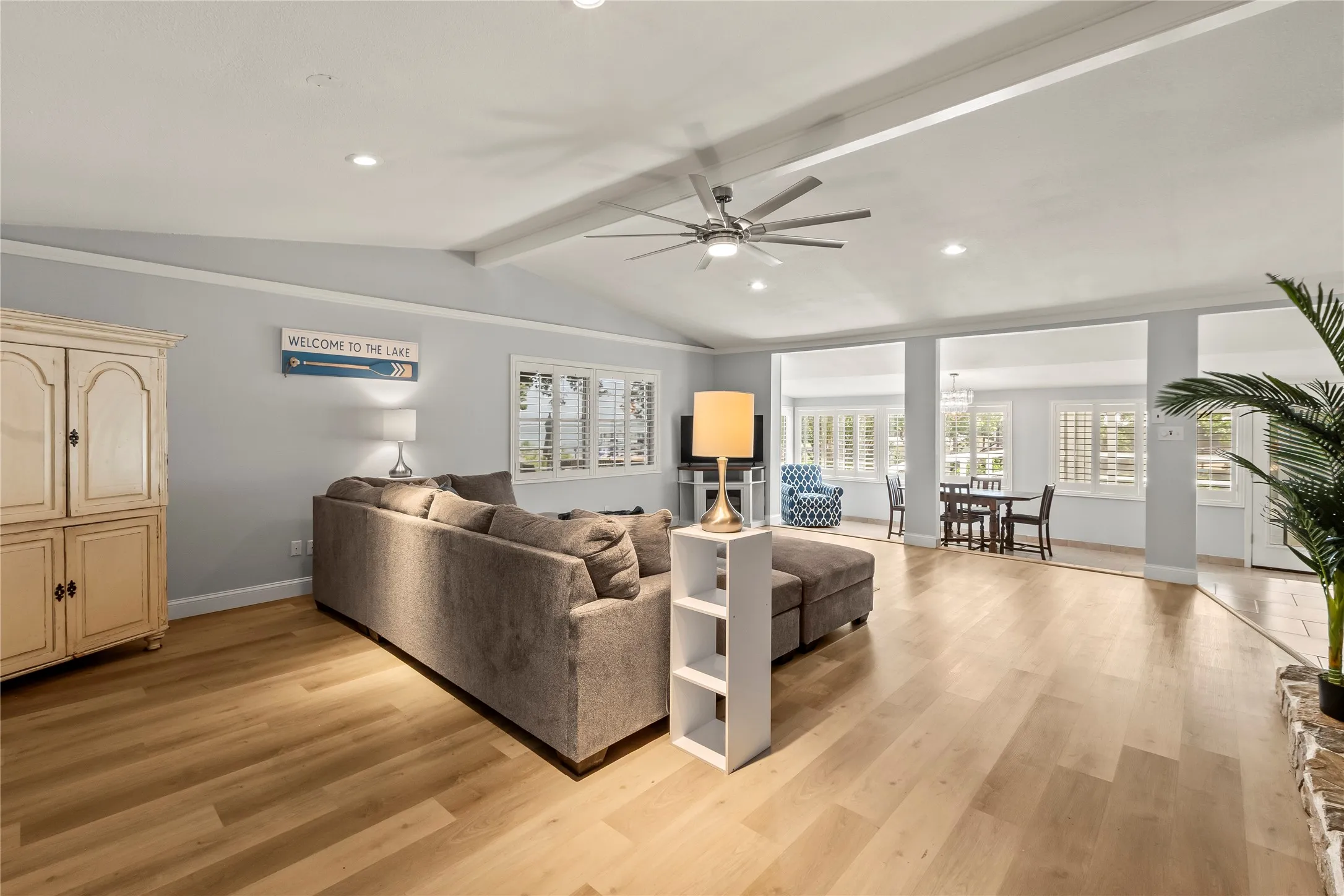 Vaulted ceiling with exposed beams, wood-finish flooring, recessed lighting, ceiling fan, and plantation shutters