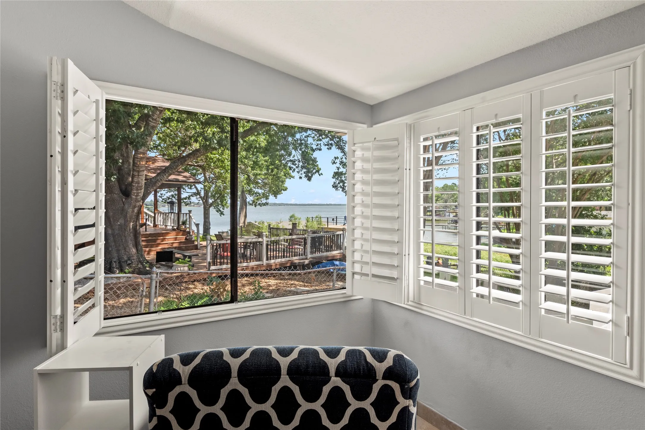 Window featuring water scenery, mature trees, and a distant structure