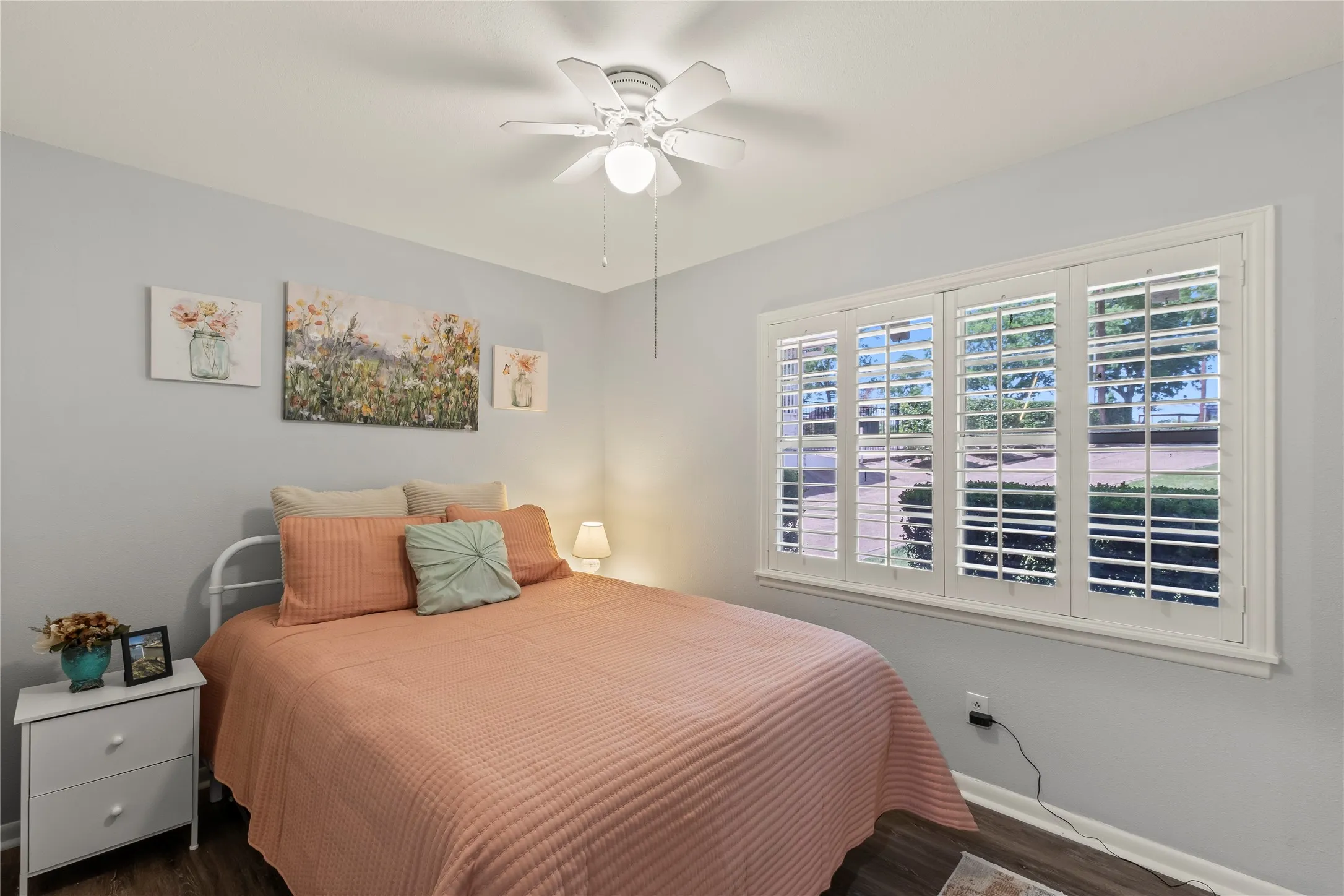 White plantation shutters, wood-finish flooring, and a ceiling fan with integrated lighting