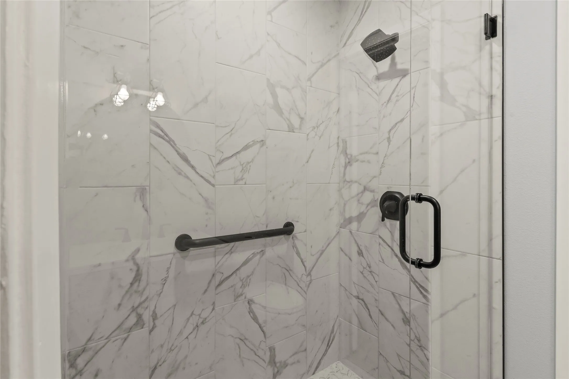 Shower with large format marble-look tile, matte black fixtures, and a glass enclosure