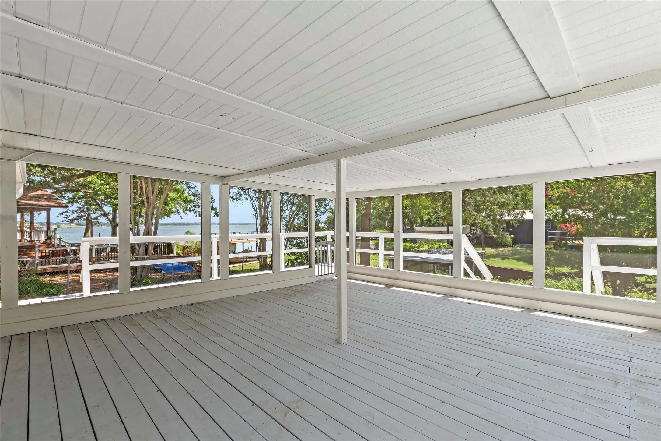 Expansive screened-in porch with a wood-finish floor and white paneling