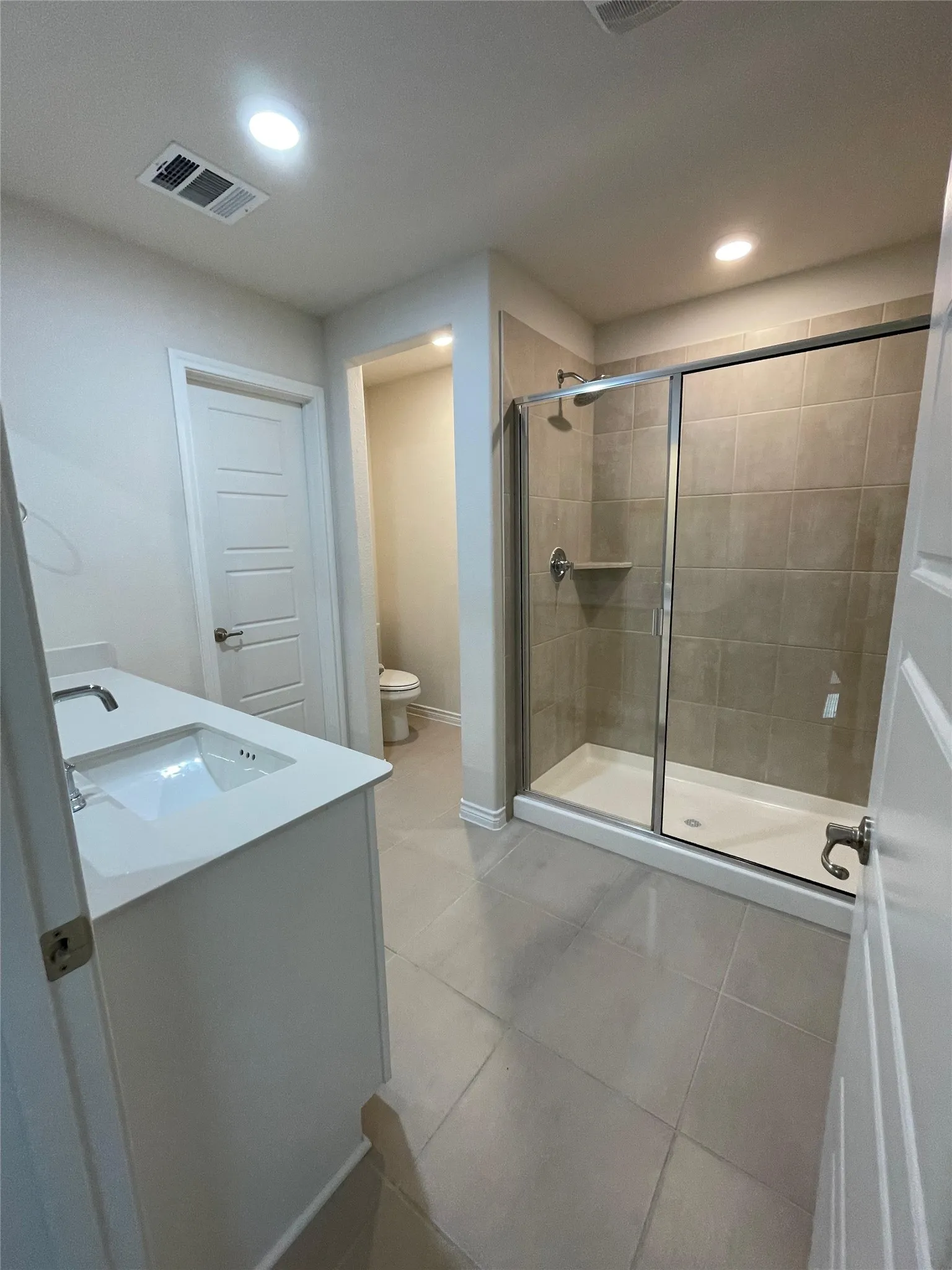 Bathroom featuring a stall shower, vanity, tile patterned flooring, and recessed lighting
