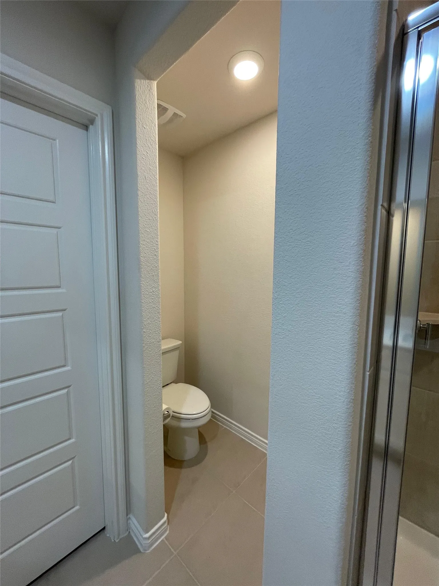 Full bath with tile patterned floors, a textured wall, and a stall shower