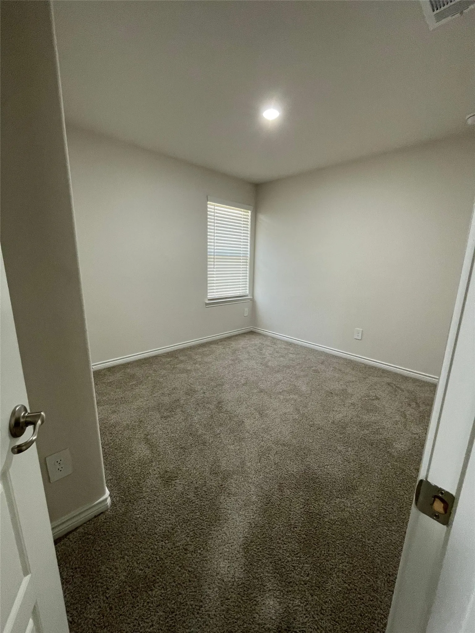 Carpeted spare room featuring baseboards