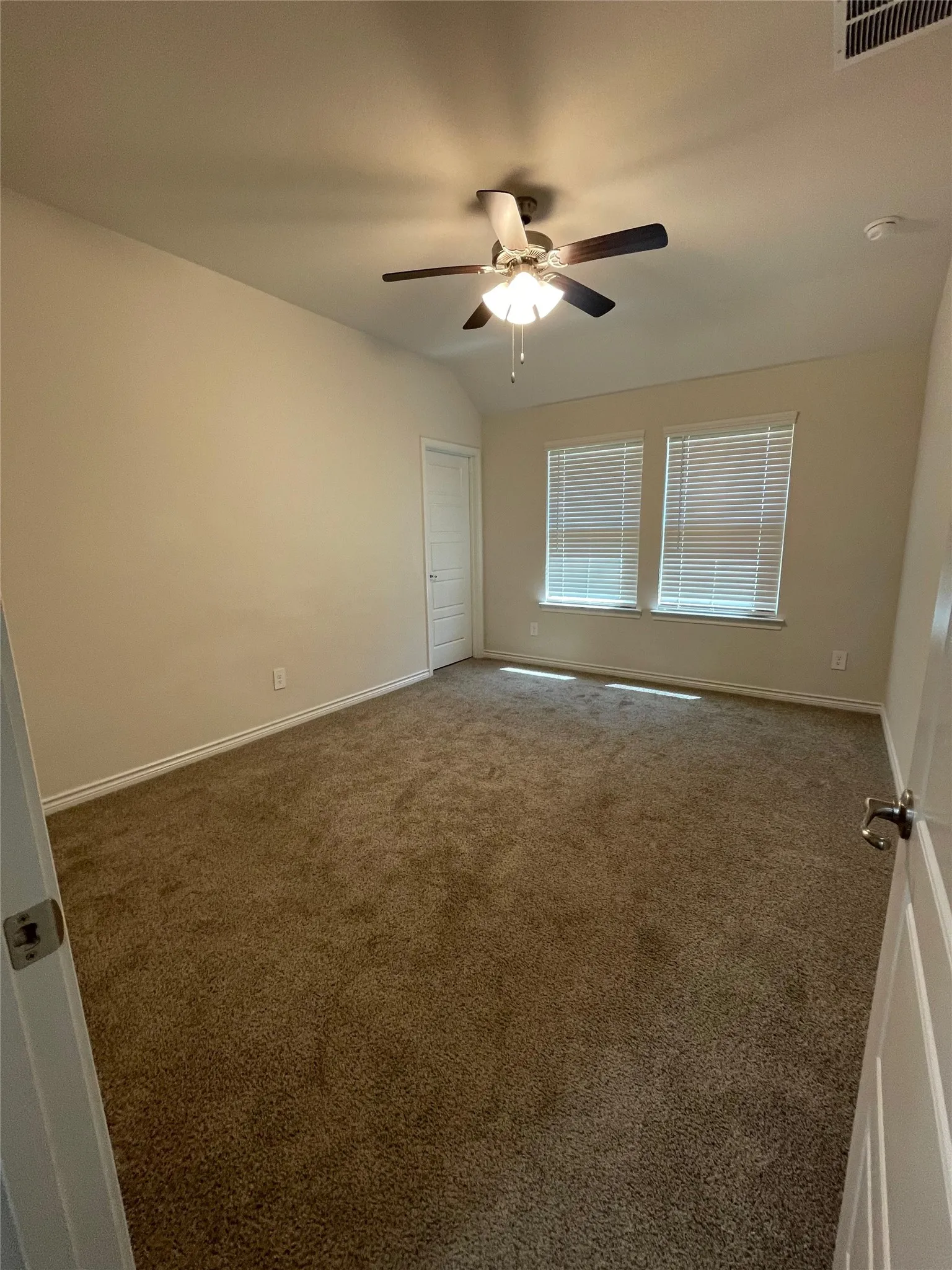 Empty room featuring ceiling fan, carpet, and lofted ceiling