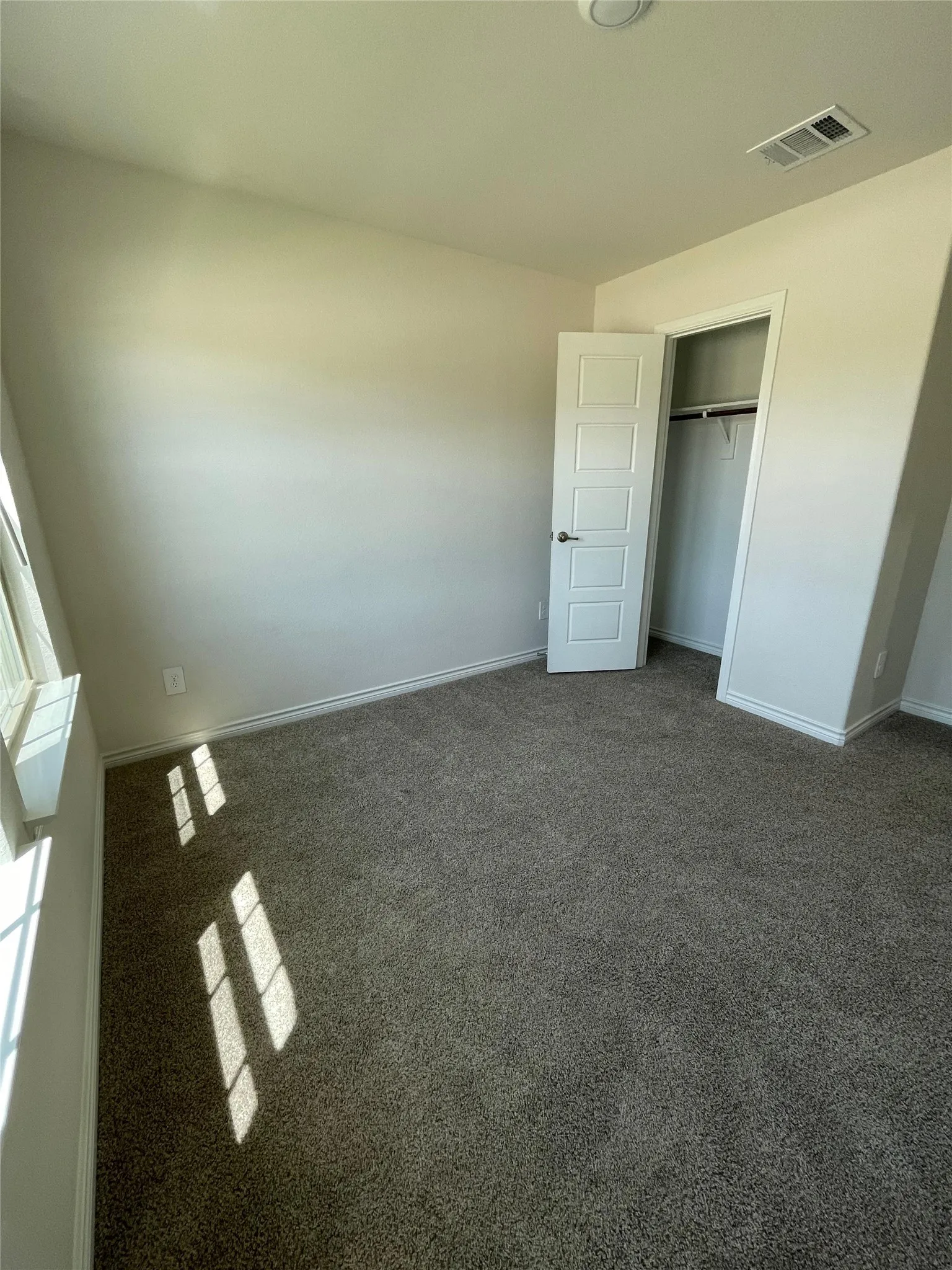 Unfurnished bedroom with dark colored carpet and a closet