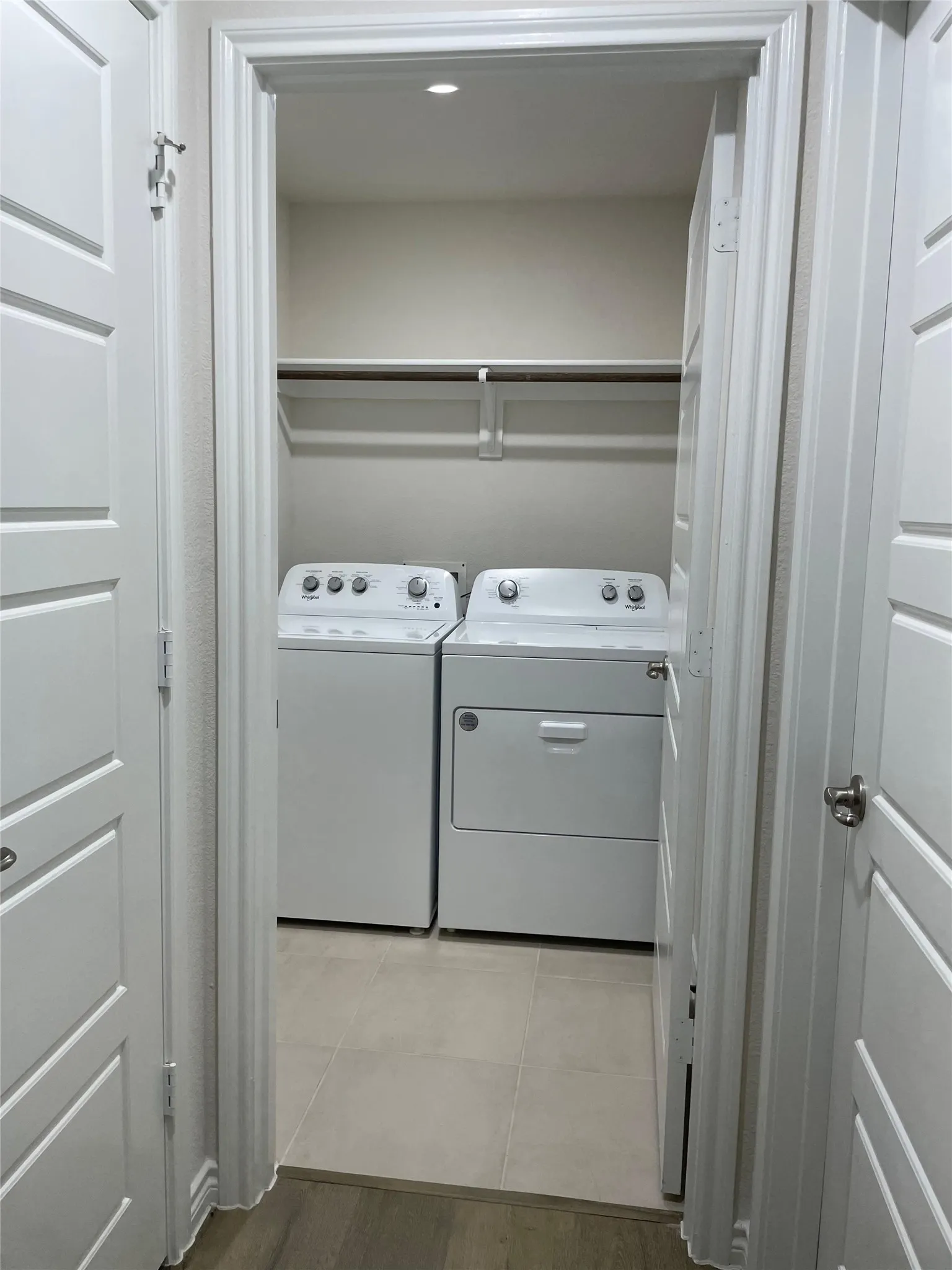 Laundry area with washing machine and dryer and light tile patterned floors