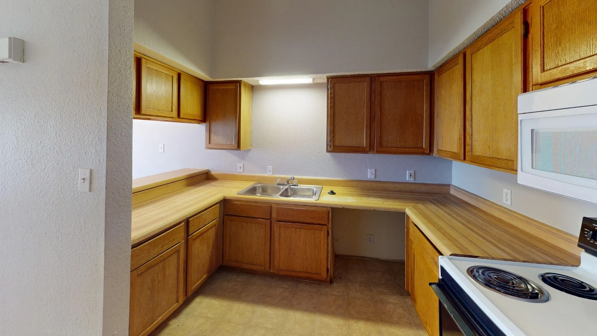 Kitchen featuring wood-finish cabinetry, wood-finish countertops, and a dual basin sink
