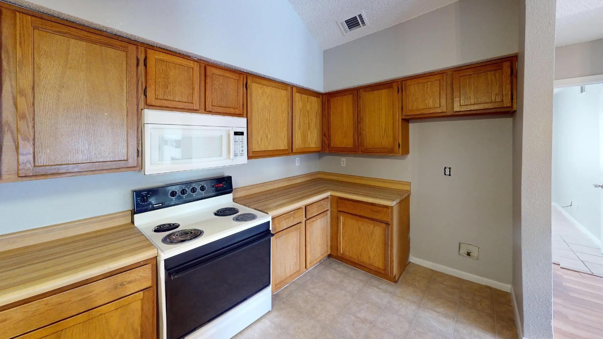 Kitchen featuring wood-finish cabinetry, a built-in microwave, white electric range, and tile flooring