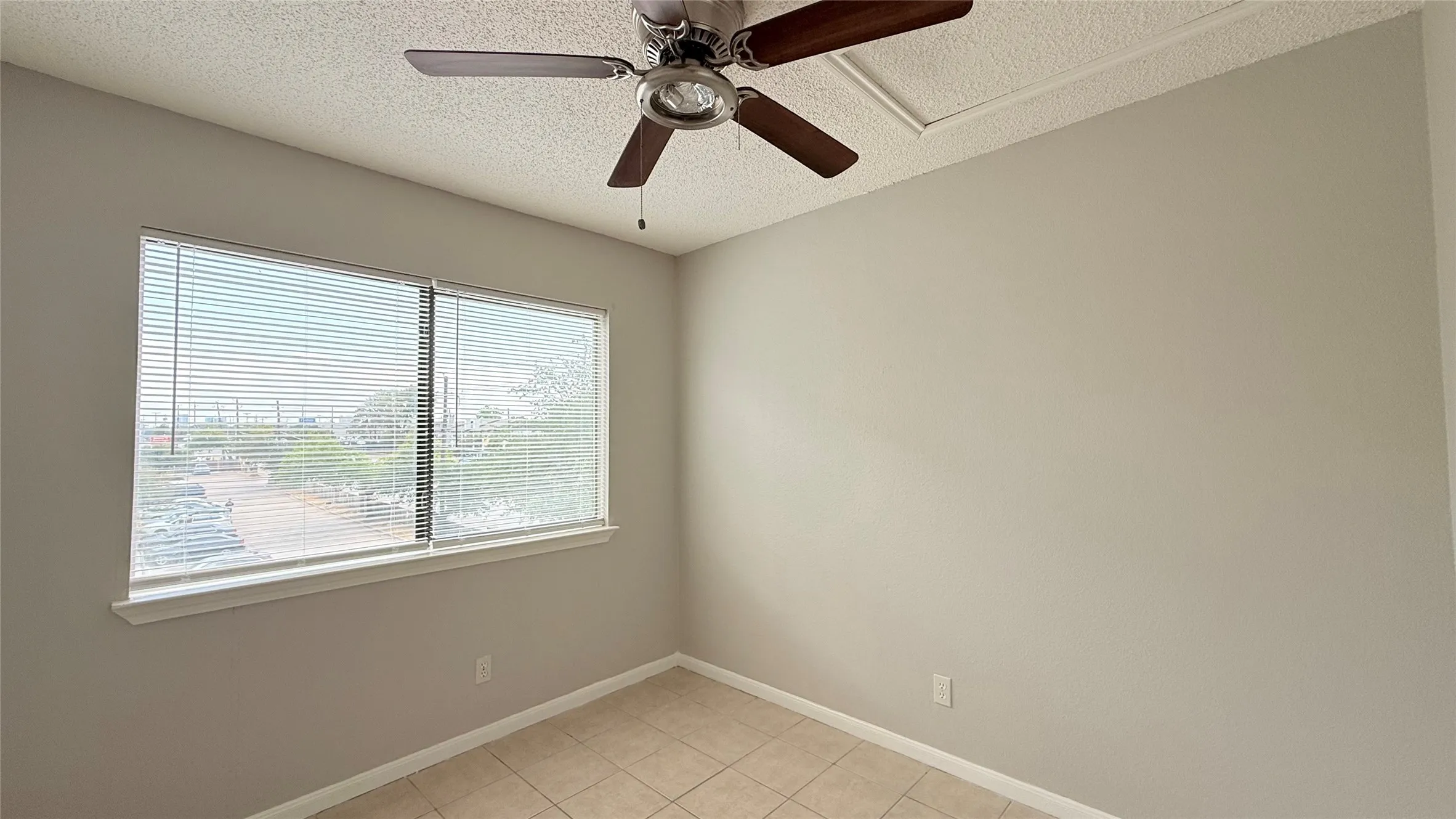 Tiled flooring, dual windows with blinds, ceiling fan with light fixture, and neutral painted walls