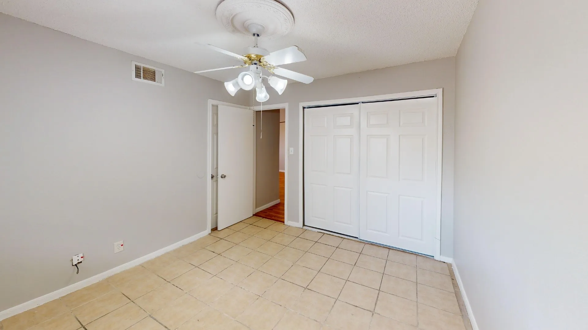 Light-toned tile flooring, ceiling-mounted fan with integrated lighting, a panel door, and sliding closet doors